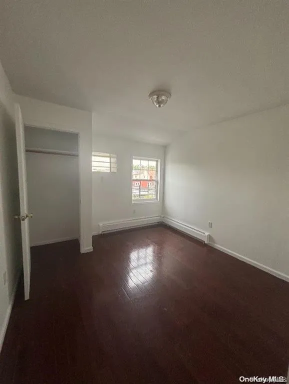Empty room featuring dark wood-style flooring, a baseboard heating unit, and a textured ceiling Empty room featuring dark wood-style flooring, a baseboard heating unit, and a textured ceiling