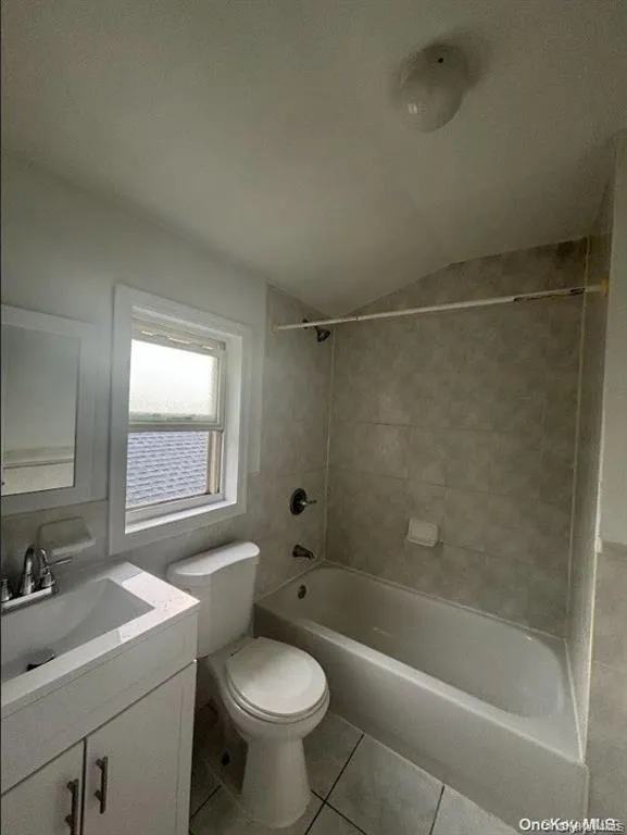 Bathroom with vanity, tile patterned floors, bathing tub / shower combination, and lofted ceiling Bathroom with vanity, tile patterned floors, bathing tub / shower combination, and lofted ceiling