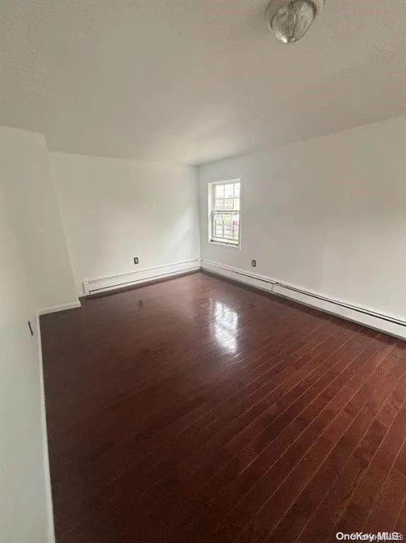 Spare room featuring dark wood-style flooring, baseboard heating, and a textured ceiling Spare room featuring dark wood-style flooring, baseboard heating, and a textured ceiling