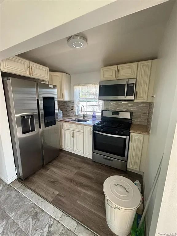 Kitchen featuring stainless steel appliances, tasteful backsplash, light countertops, and dark wood finished floors Kitchen featuring stainless steel appliances, tasteful backsplash, light countertops, and dark wood finished floors