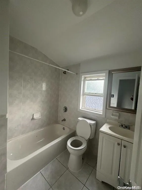 Bathroom featuring light tile patterned floors, vanity, bathtub / shower combination, and lofted ceiling Bathroom featuring light tile patterned floors, vanity, bathtub / shower combination, and lofted ceiling