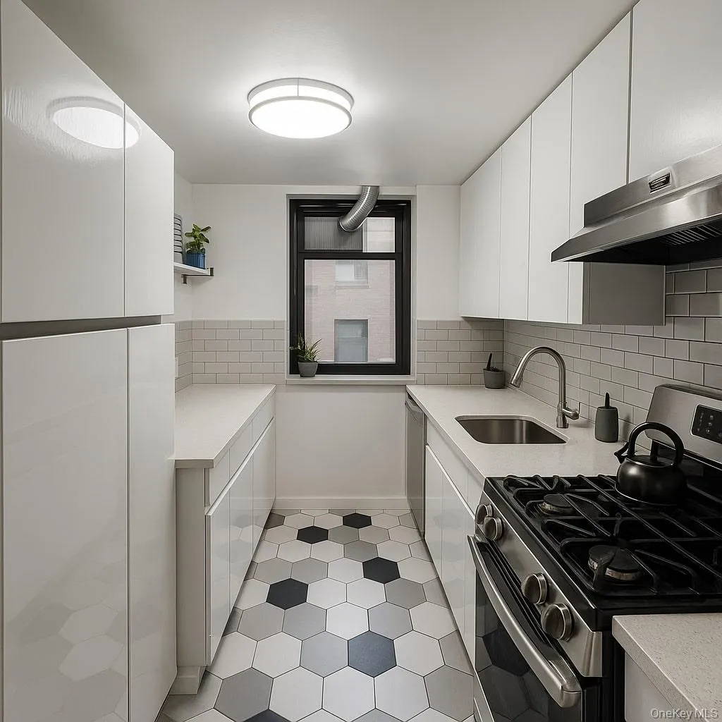 Kitchen with appliances with stainless steel finishes, white cabinetry, modern cabinets, and decorative backsplash Kitchen with appliances with stainless steel finishes, white cabinetry, modern cabinets, and decorative backsplash