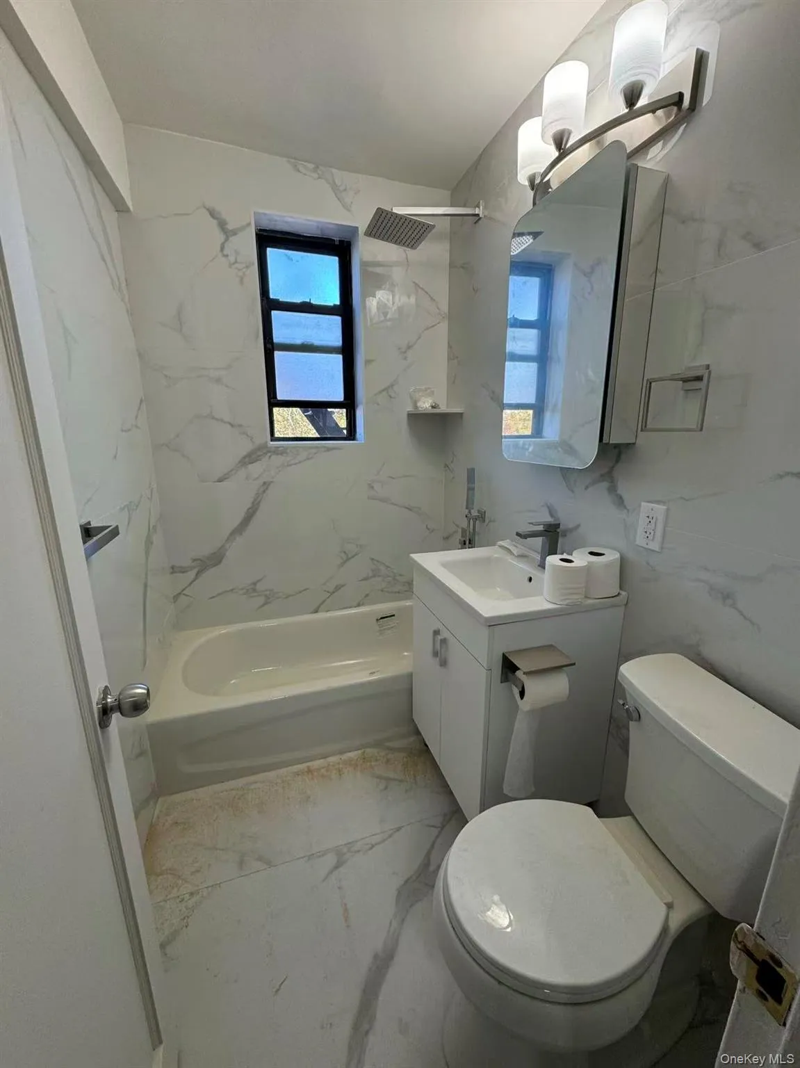 Full bath with light marble finish floors, vanity, a combined bath / shower with marble appearance, and tile walls Full bath with light marble finish floors, vanity, a combined bath / shower with marble appearance, and tile walls