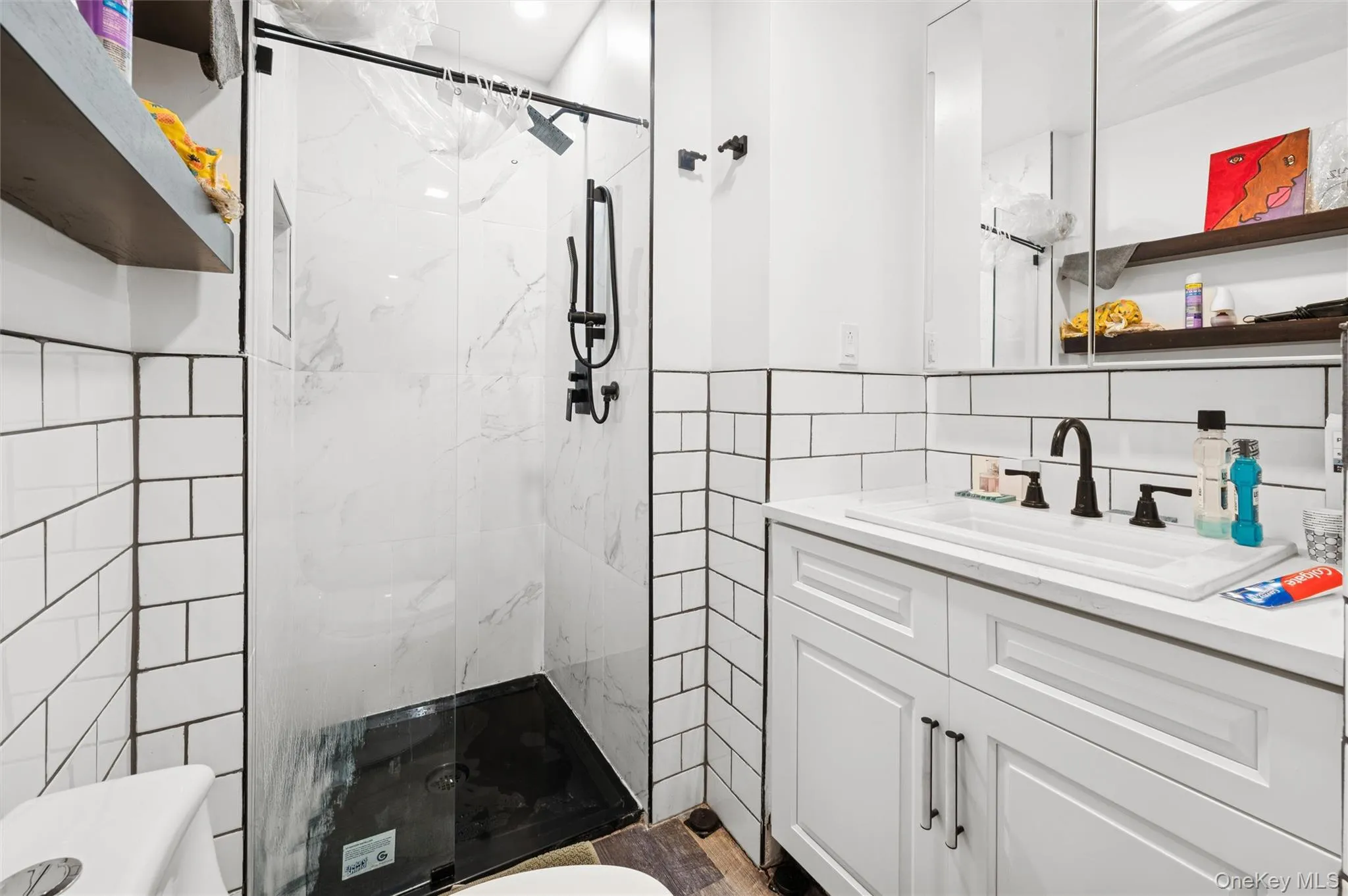 Full bath featuring tile walls, vanity, and a marble finish shower Full bath featuring tile walls, vanity, and a marble finish shower