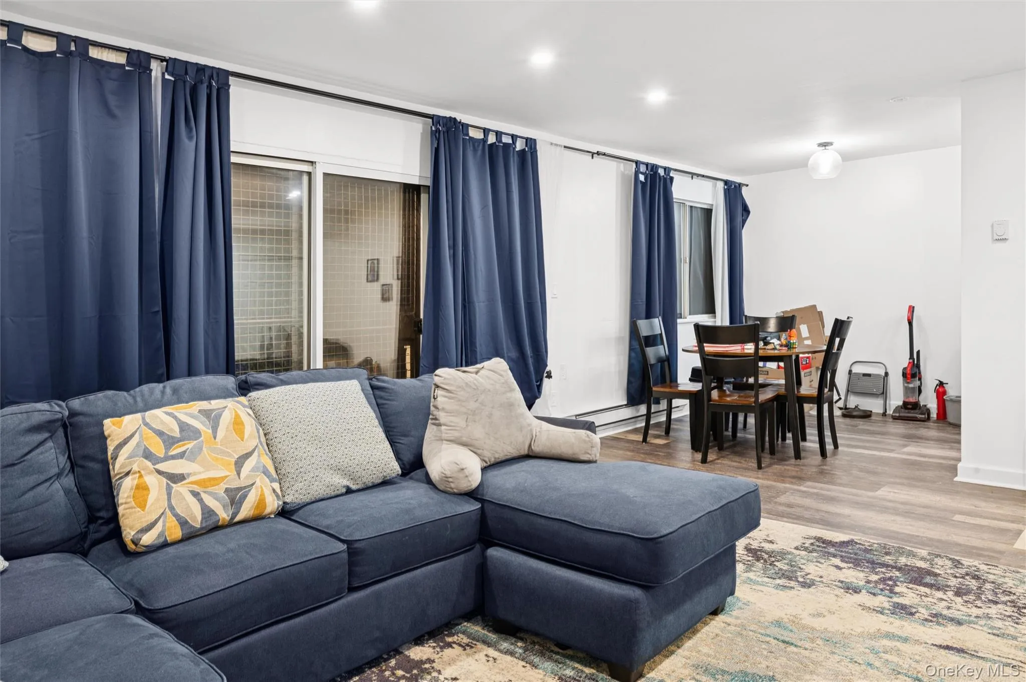 Living room with wood finished floors, recessed lighting, and a baseboard radiator Living room with wood finished floors, recessed lighting, and a baseboard radiator