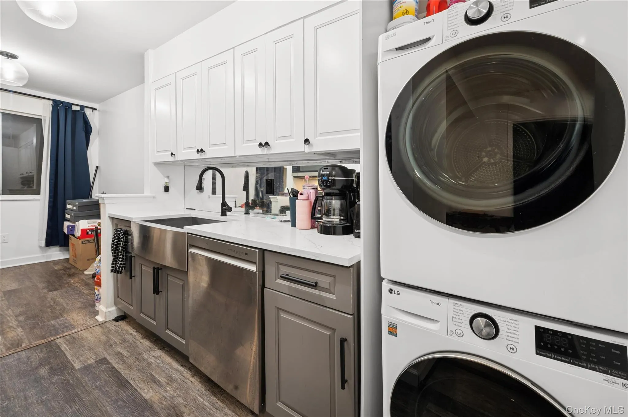 Laundry room with dark wood-style flooring and stacked washer / drying machine Laundry room with dark wood-style flooring and stacked washer / drying machine