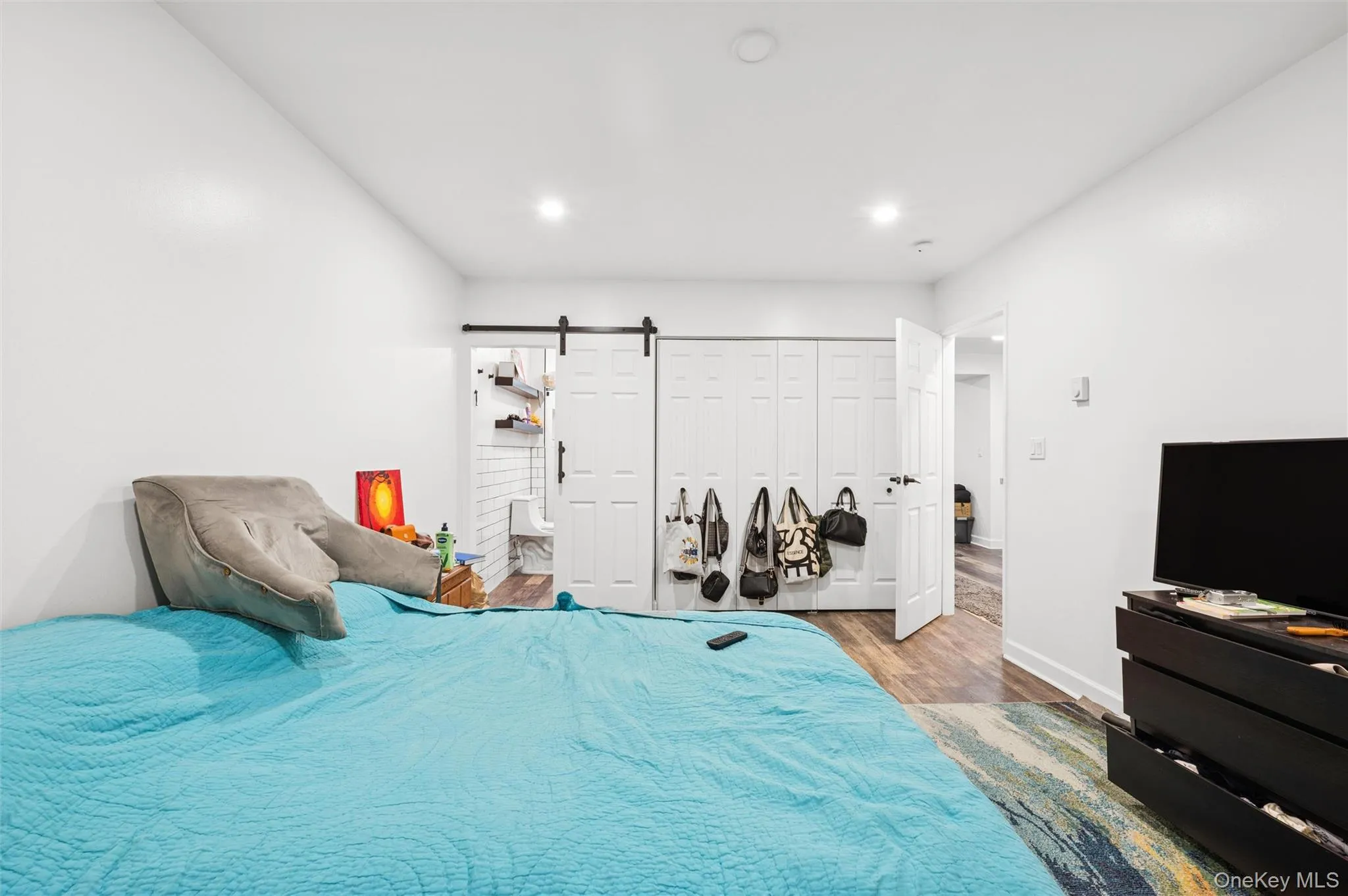Bedroom featuring wood finished floors, a barn door, and recessed lighting Bedroom featuring wood finished floors, a barn door, and recessed lighting