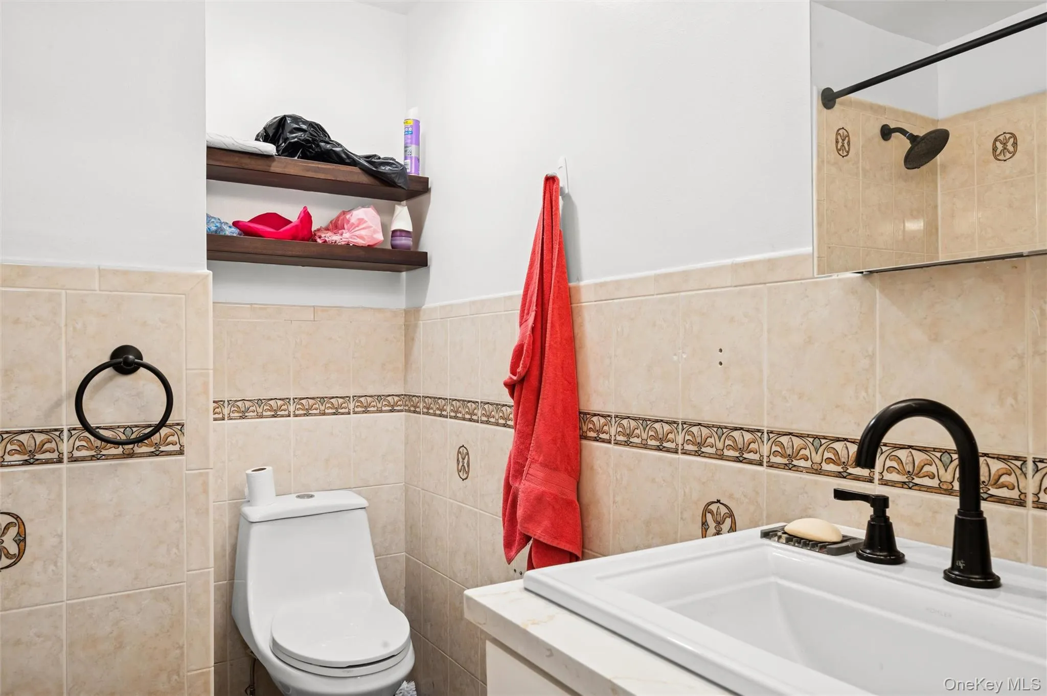 Full bathroom featuring tile walls, vanity, a wainscoted wall, and a shower Full bathroom featuring tile walls, vanity, a wainscoted wall, and a shower