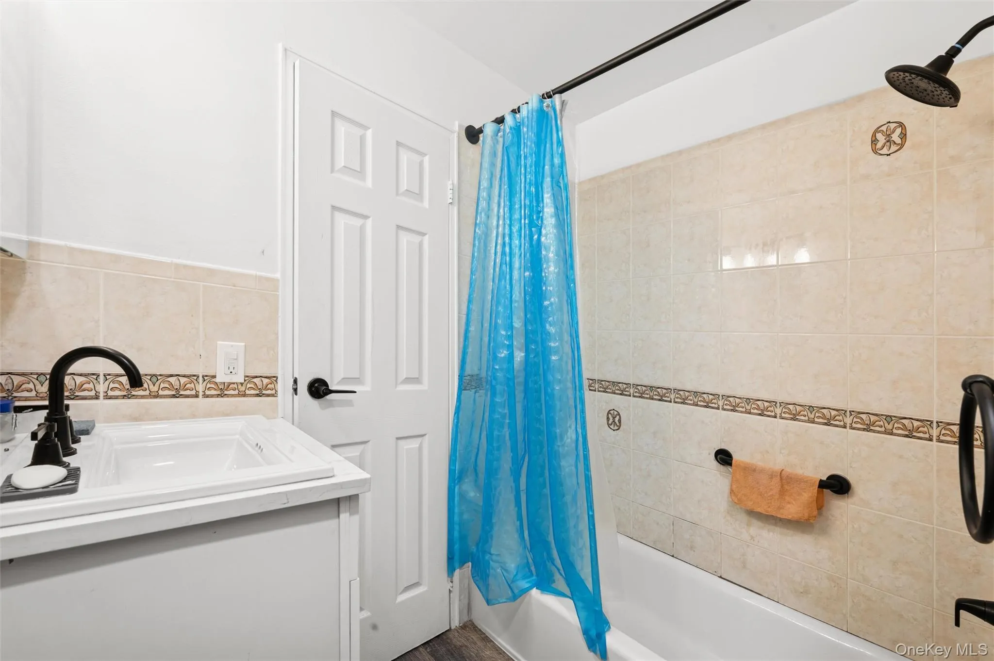 Bathroom with vanity, shower / bath combo with shower curtain, and tile walls Bathroom with vanity, shower / bath combo with shower curtain, and tile walls