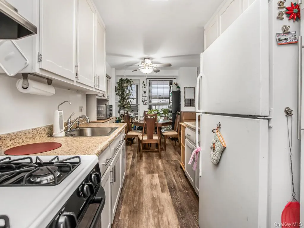 Kitchen with freestanding refrigerator, gas stove, dark wood-type flooring, exhaust hood, and ceiling fan Kitchen with freestanding refrigerator, gas stove, dark wood-type flooring, exhaust hood, and ceiling fan