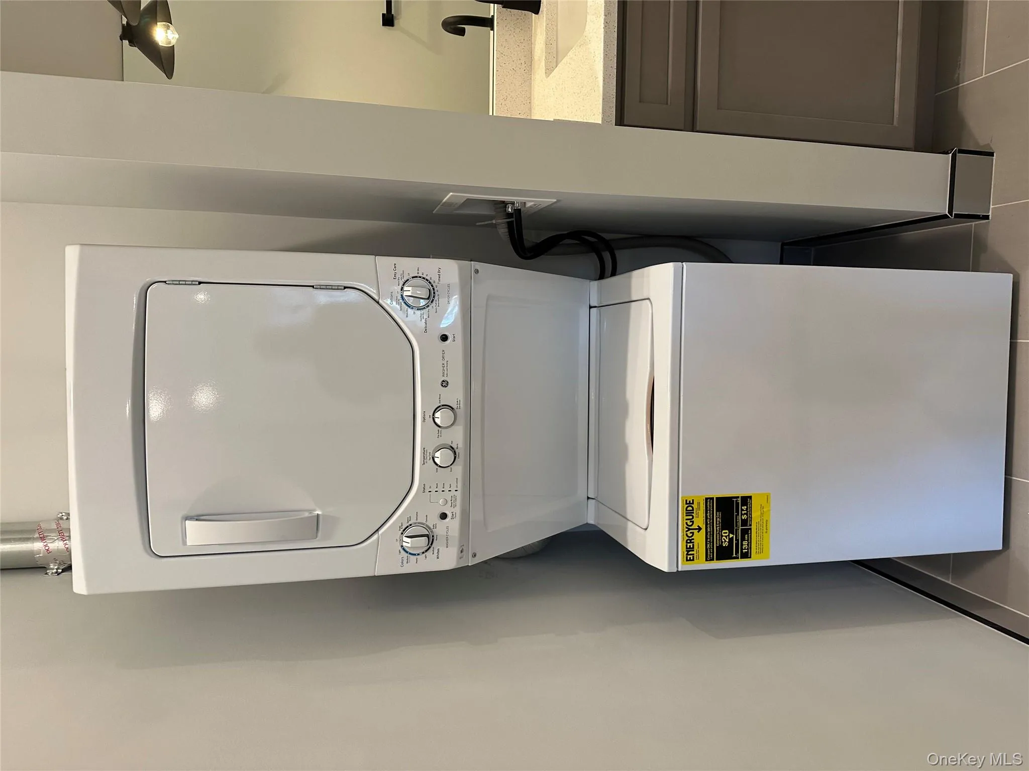 Laundry area featuring light tile patterned floors and stacked washer and clothes dryer Laundry area featuring light tile patterned floors and stacked washer and clothes dryer