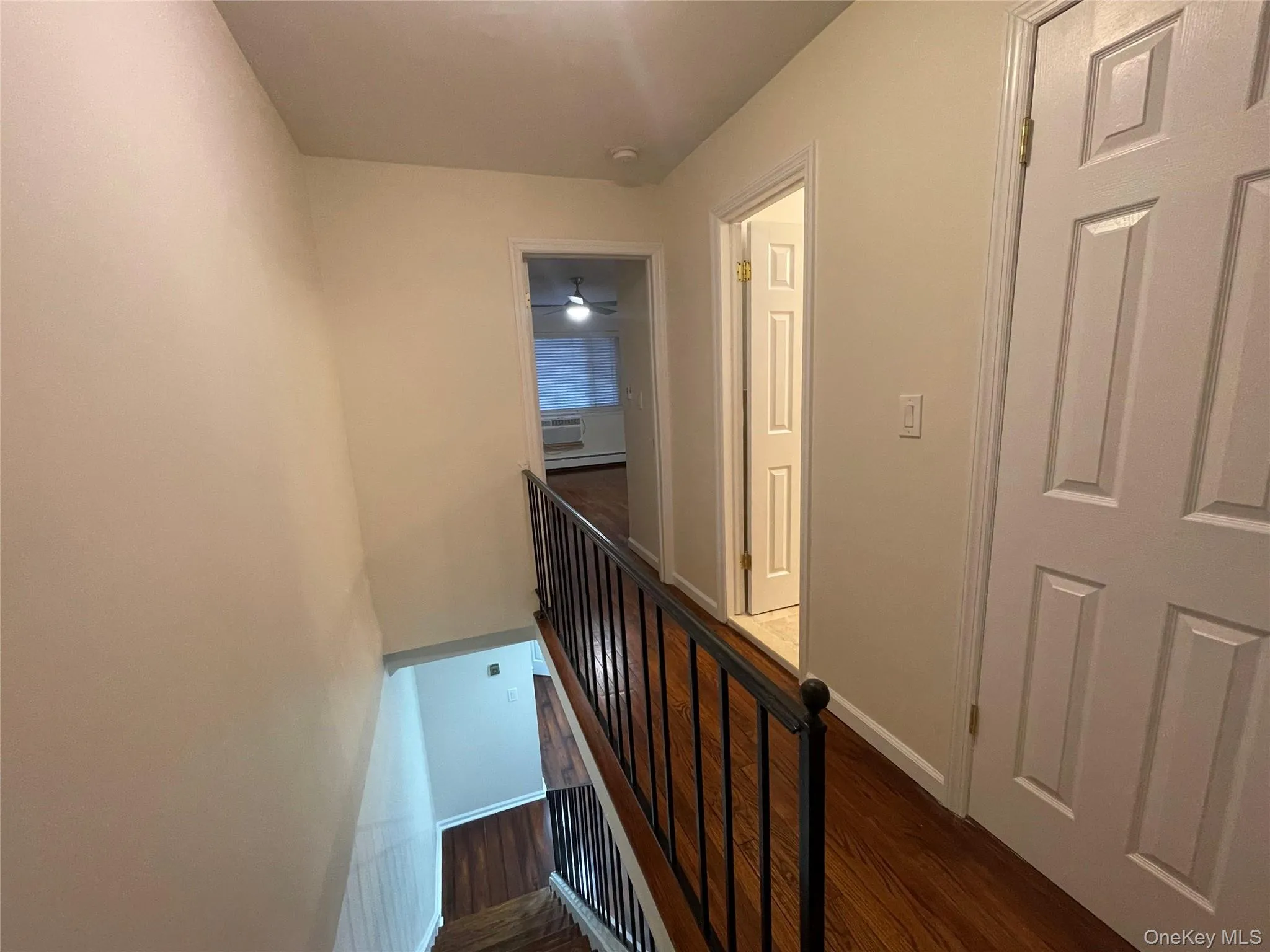 Hall featuring an upstairs landing, dark wood-style flooring, and a baseboard heating unit Hall featuring an upstairs landing, dark wood-style flooring, and a baseboard heating unit