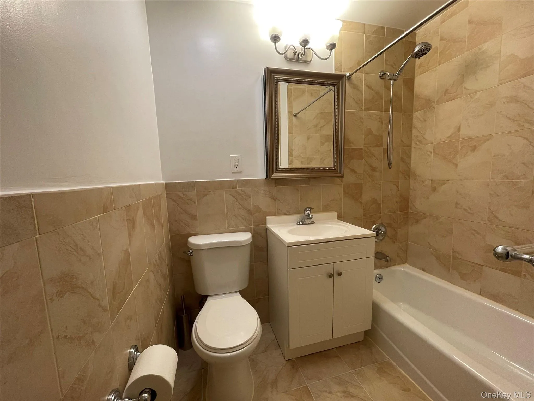 Bathroom with vanity, tile walls, bathtub / shower combination, and wainscoting Bathroom with vanity, tile walls, bathtub / shower combination, and wainscoting
