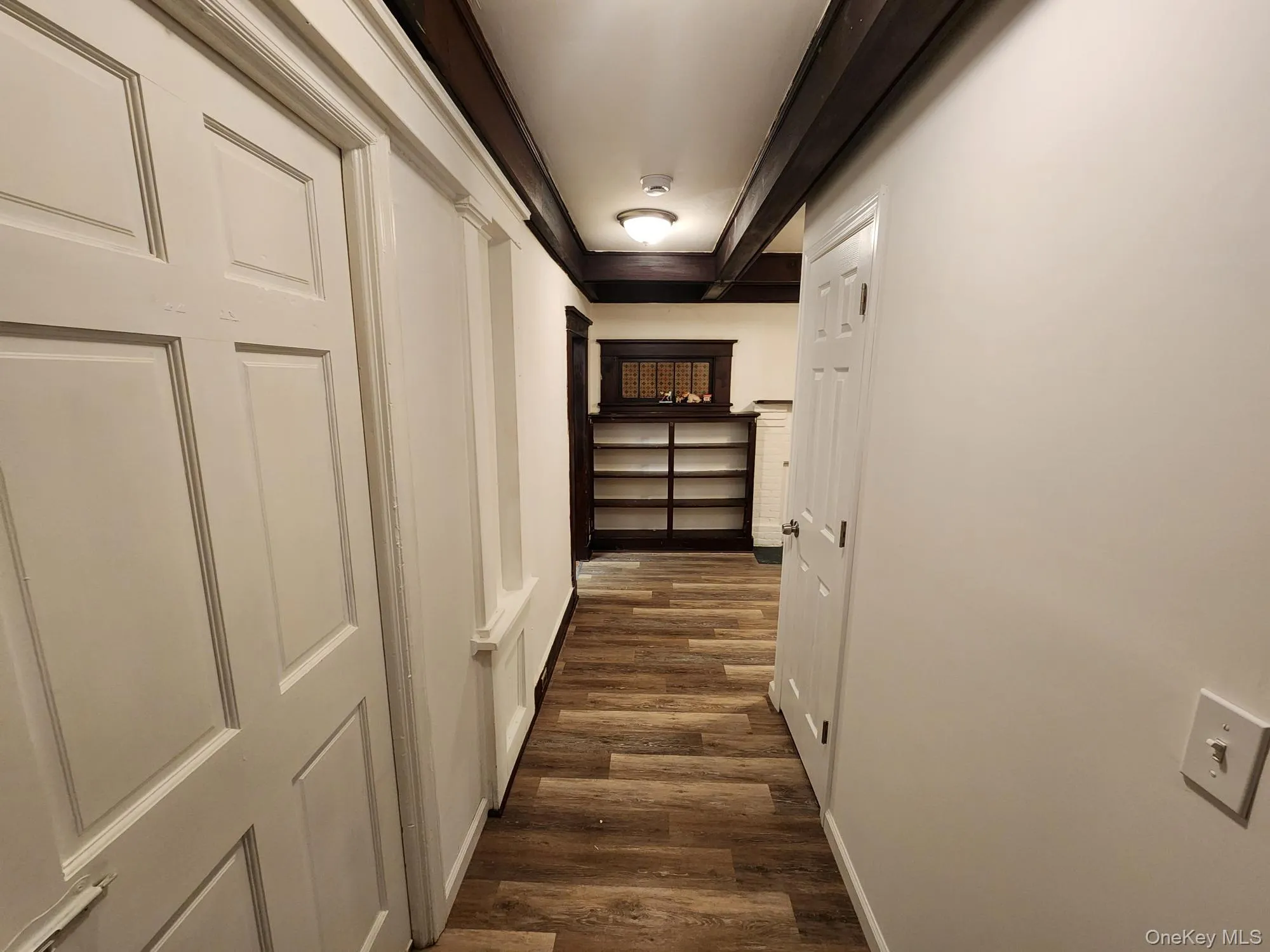 Hallway with dark wood-style flooring and beamed ceiling Hallway with dark wood-style flooring and beamed ceiling
