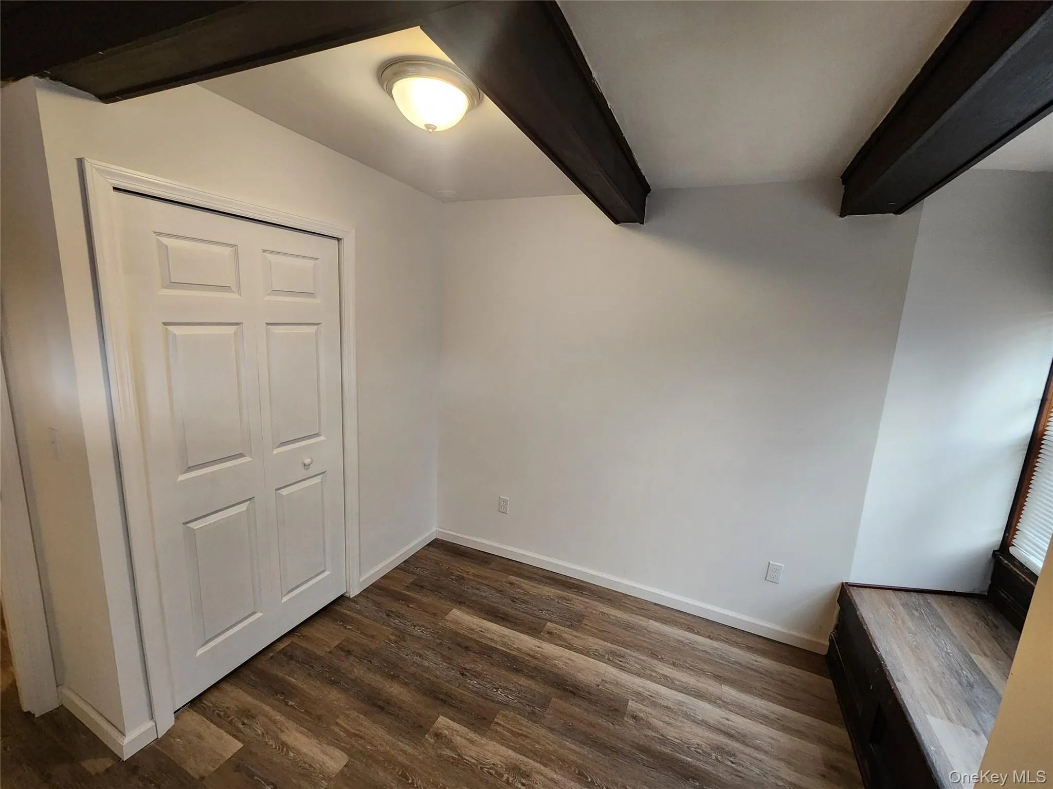 Unfurnished bedroom with dark wood-type flooring, beam ceiling, and a closet Unfurnished bedroom with dark wood-type flooring, beam ceiling, and a closet