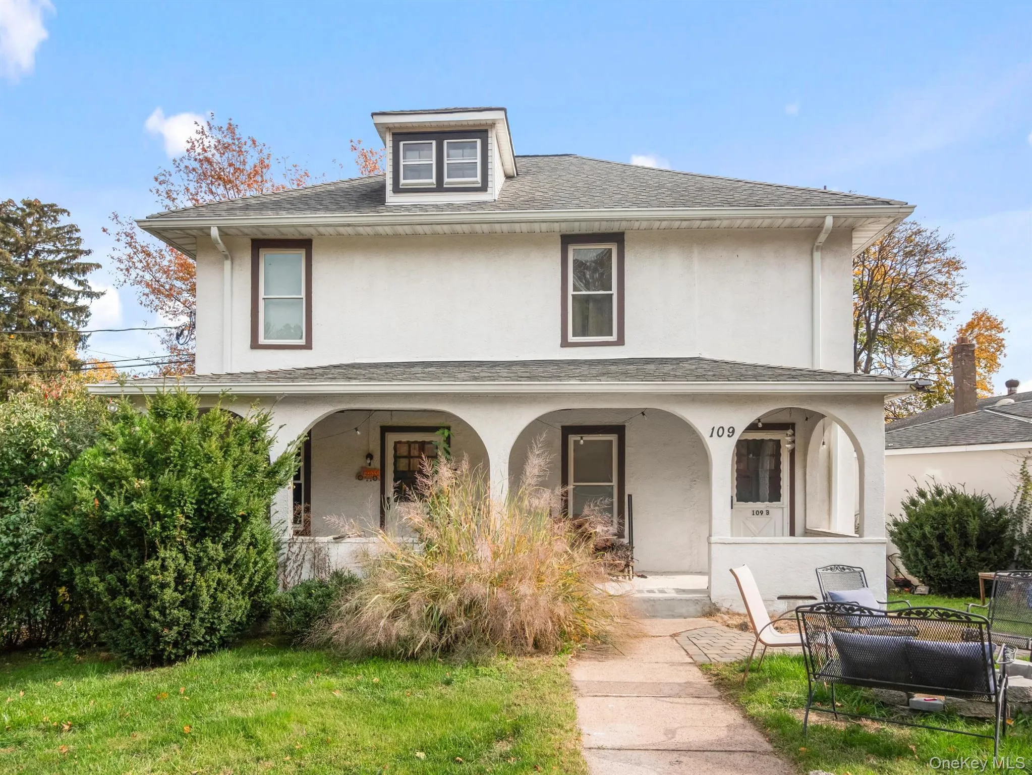 View of front of house with stucco siding, a porch, a front yard, and roof with shingles View of front of house with stucco siding, a porch, a front yard, and roof with shingles