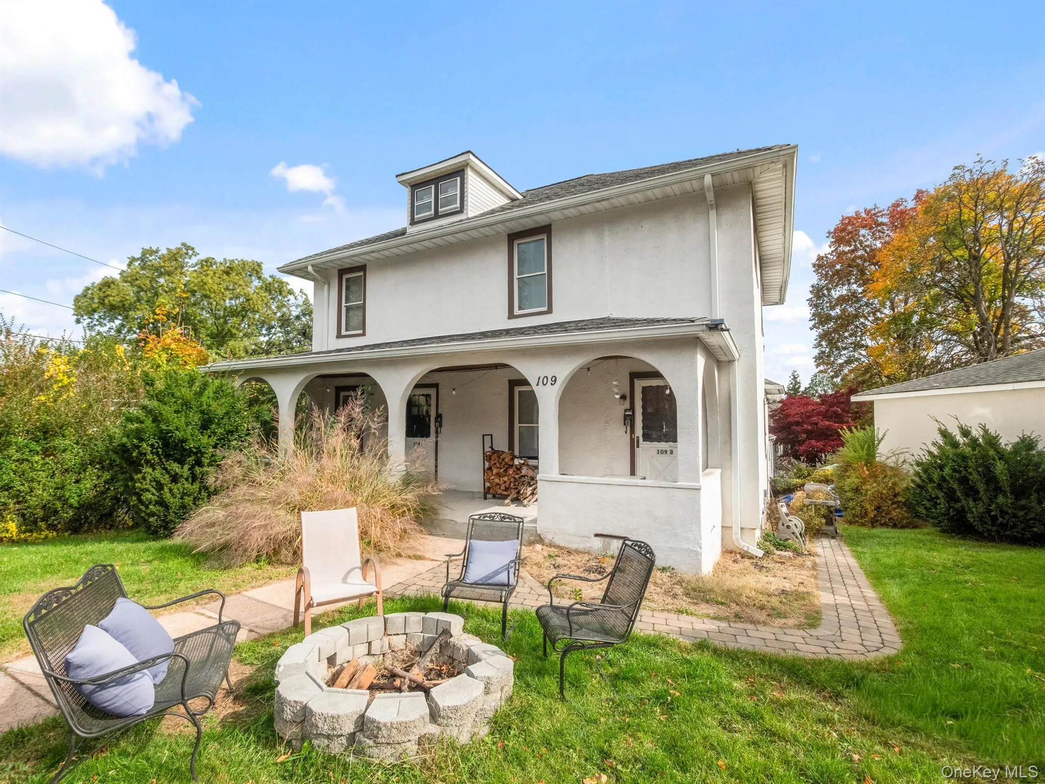 Back of property with a lawn, stucco siding, an outdoor fire pit, and a porch Back of property with a lawn, stucco siding, an outdoor fire pit, and a porch