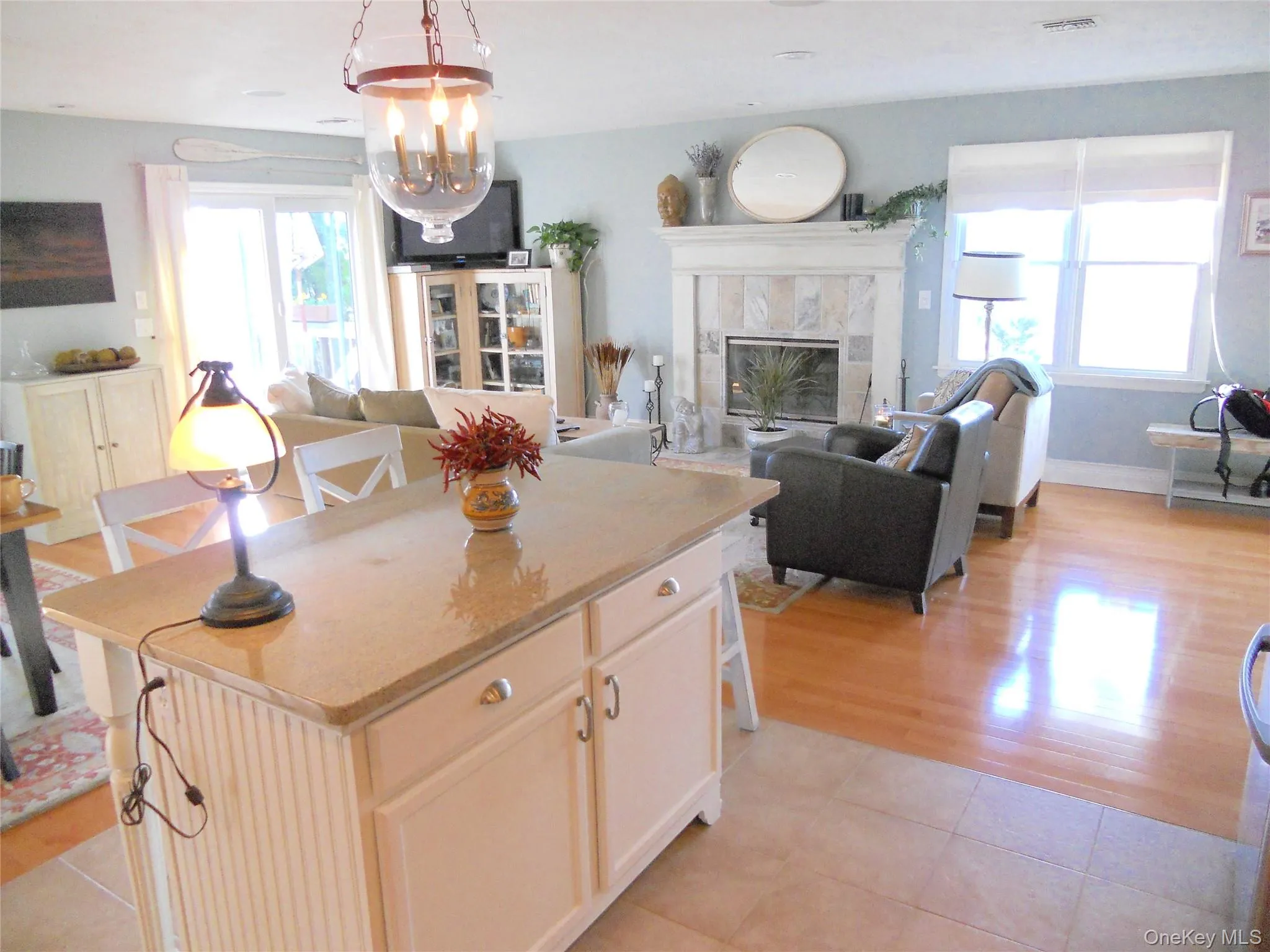 Kitchen with open floor plan, a tiled fireplace, light stone counters, light tile patterned floors, and a breakfast bar area Kitchen with open floor plan, a tiled fireplace, light stone counters, light tile patterned floors, and a breakfast bar area