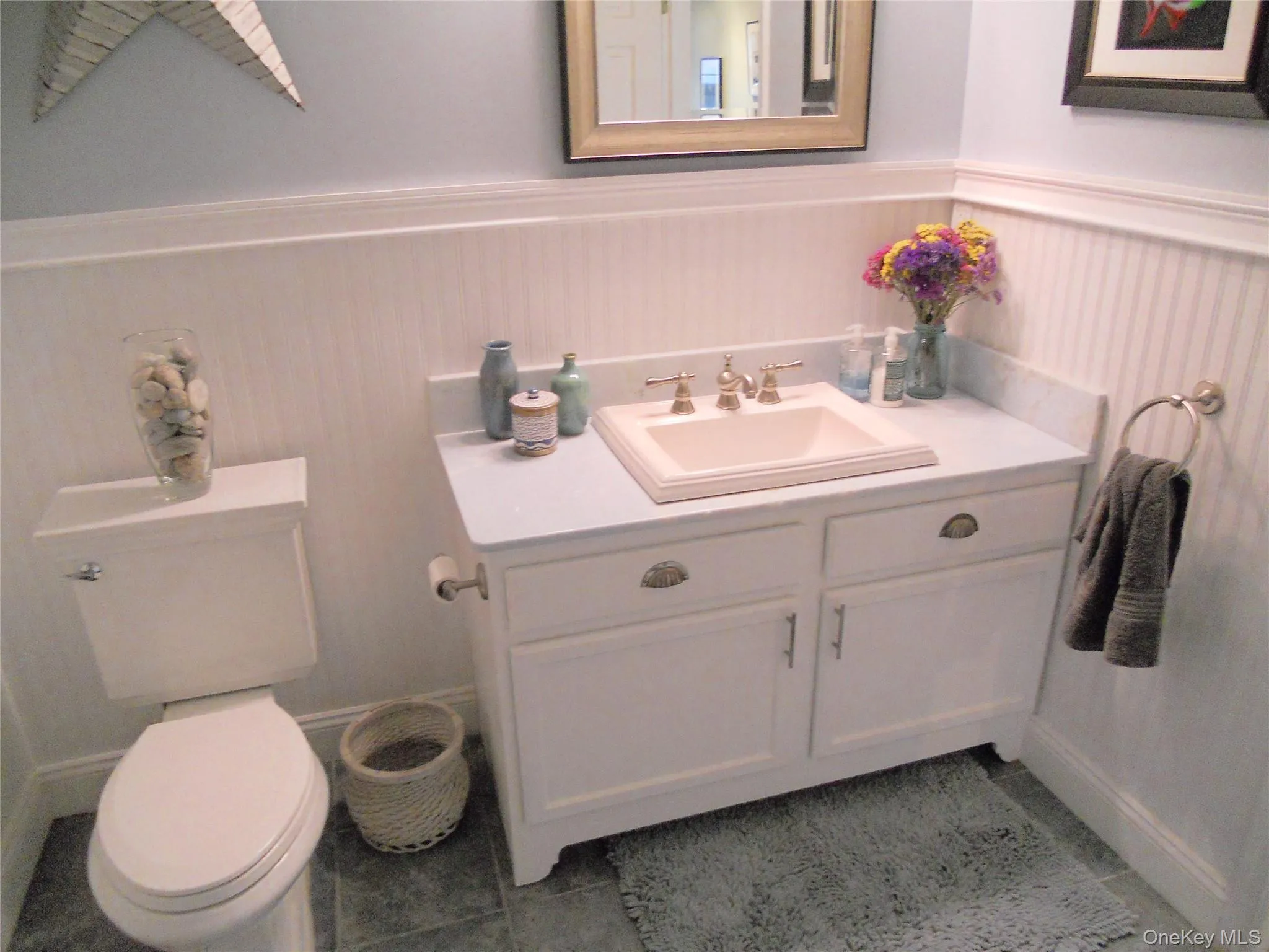 Bathroom featuring vanity, light tile patterned floors, and a wainscoted wall Bathroom featuring vanity, light tile patterned floors, and a wainscoted wall