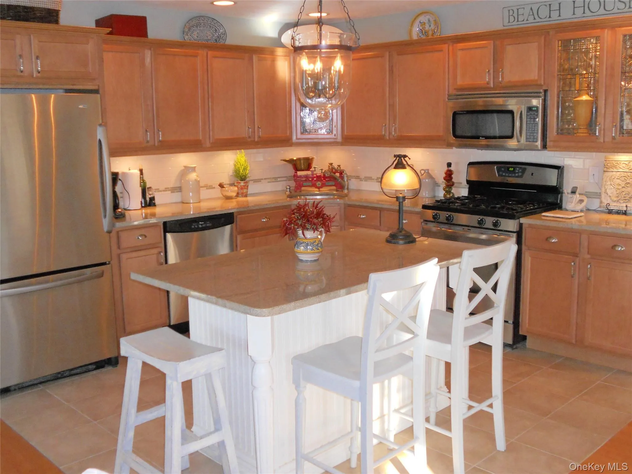 Kitchen featuring appliances with stainless steel finishes, a center island, decorative backsplash, and light tile patterned flooring Kitchen featuring appliances with stainless steel finishes, a center island, decorative backsplash, and light tile patterned flooring