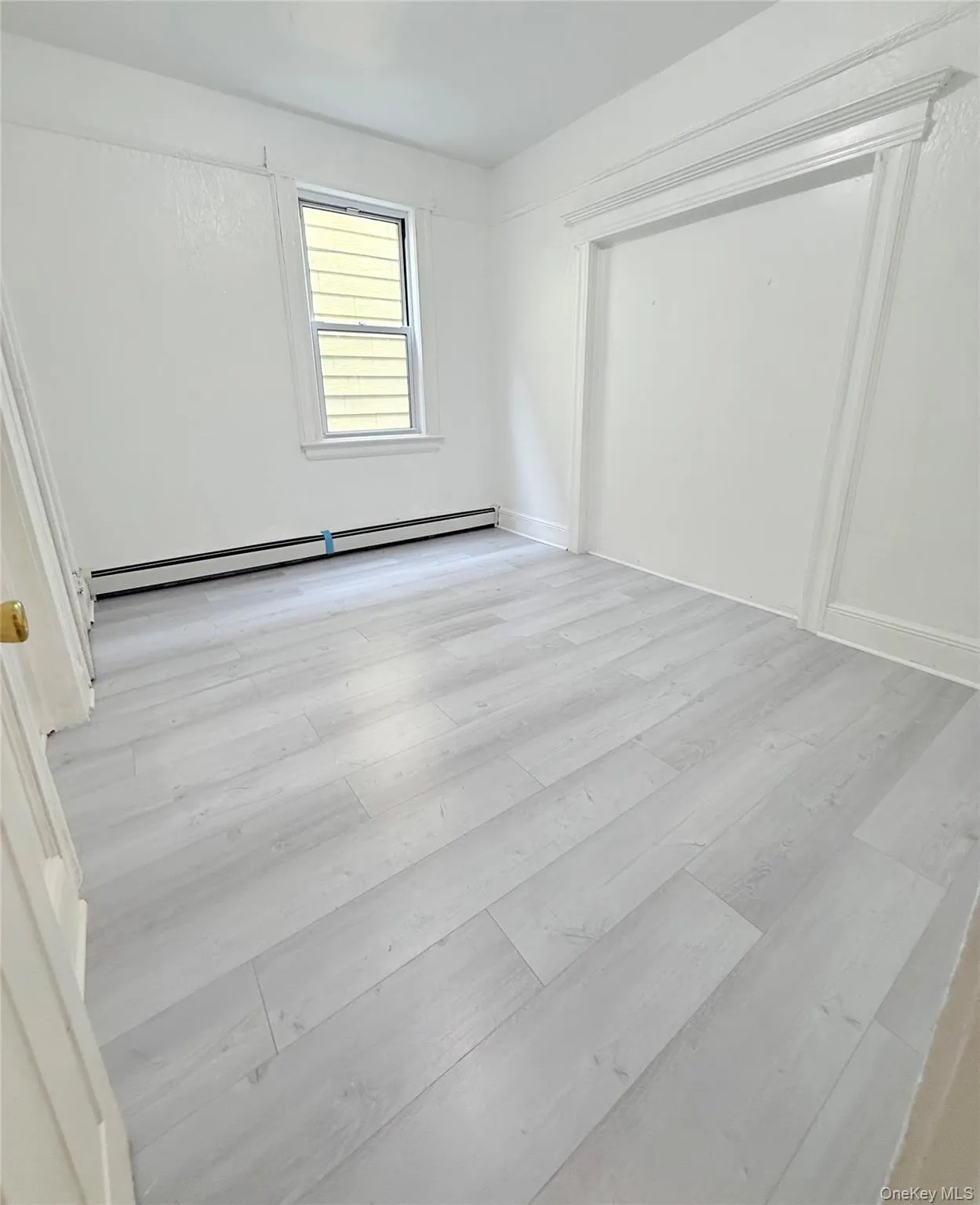 Unfurnished bedroom featuring light wood-type flooring and a baseboard heating unit Unfurnished bedroom featuring light wood-type flooring and a baseboard heating unit