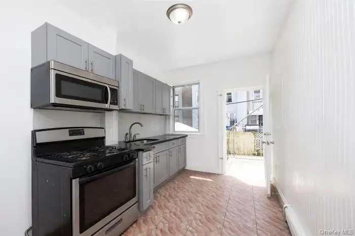 Kitchen featuring stainless steel appliances, gray cabinetry, and baseboard heating Kitchen featuring stainless steel appliances, gray cabinetry, and baseboard heating
