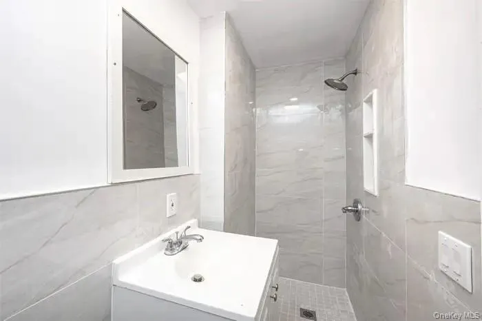 Bathroom featuring a stall shower, tile walls, and vanity Bathroom featuring a stall shower, tile walls, and vanity