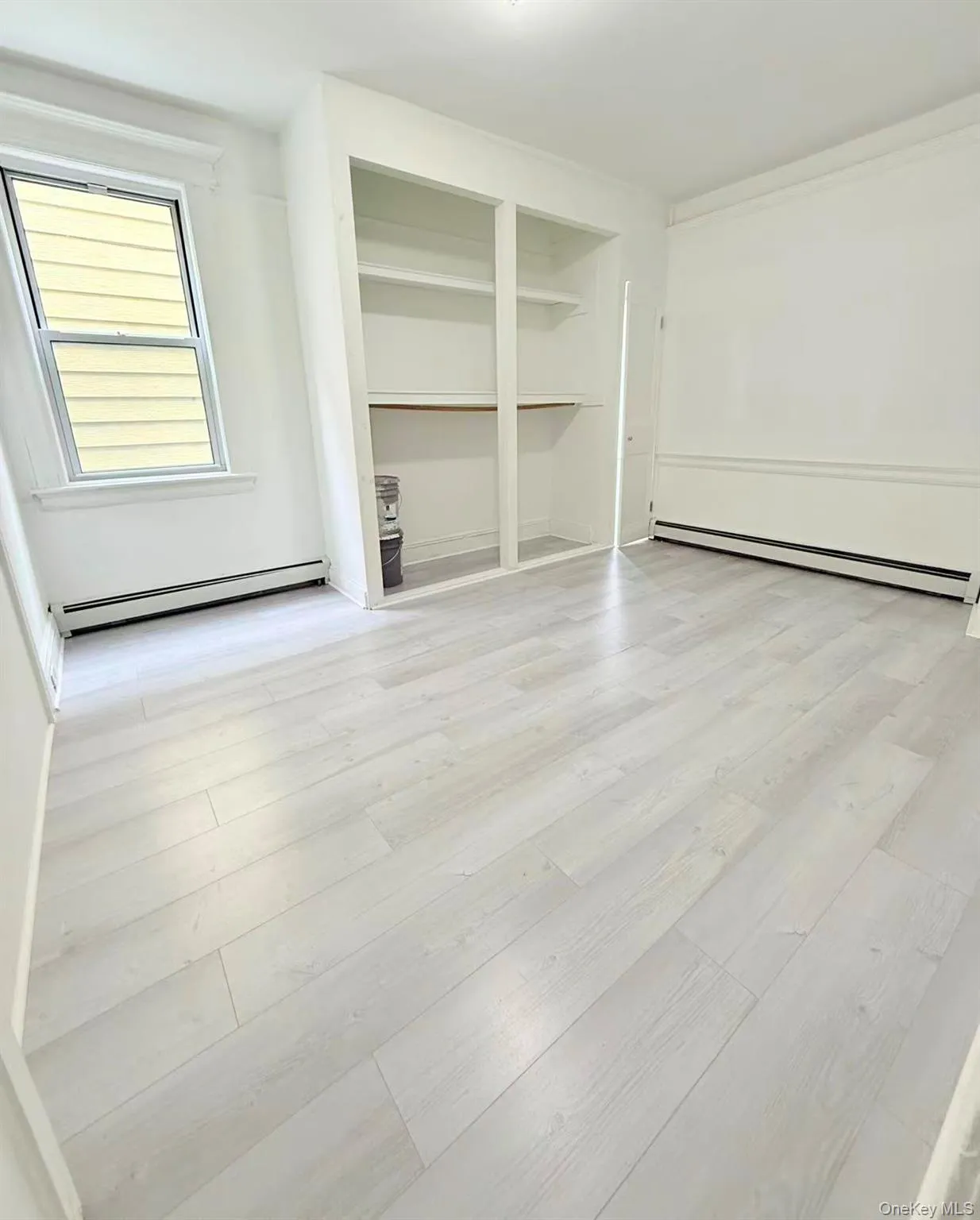 Unfurnished room with a baseboard radiator and light wood-style floors Unfurnished room with a baseboard radiator and light wood-style floors