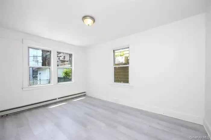 Empty room featuring a baseboard radiator and wood finished floors Empty room featuring a baseboard radiator and wood finished floors