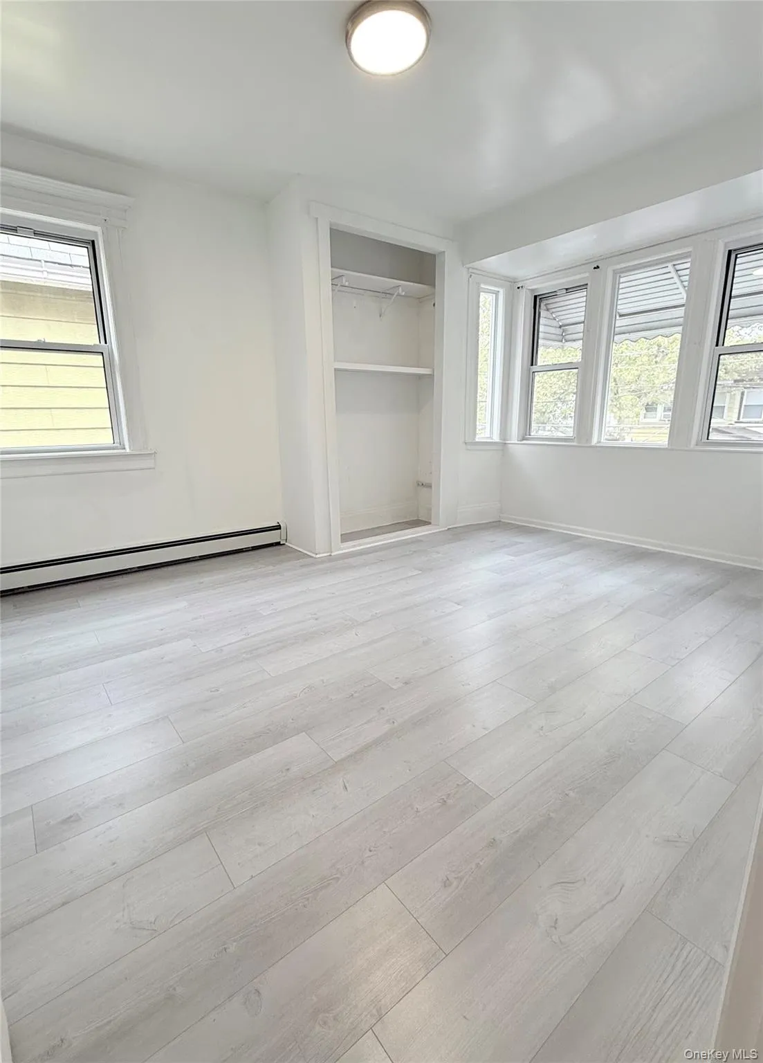 Spare room featuring baseboard heating and light wood-style floors Spare room featuring baseboard heating and light wood-style floors
