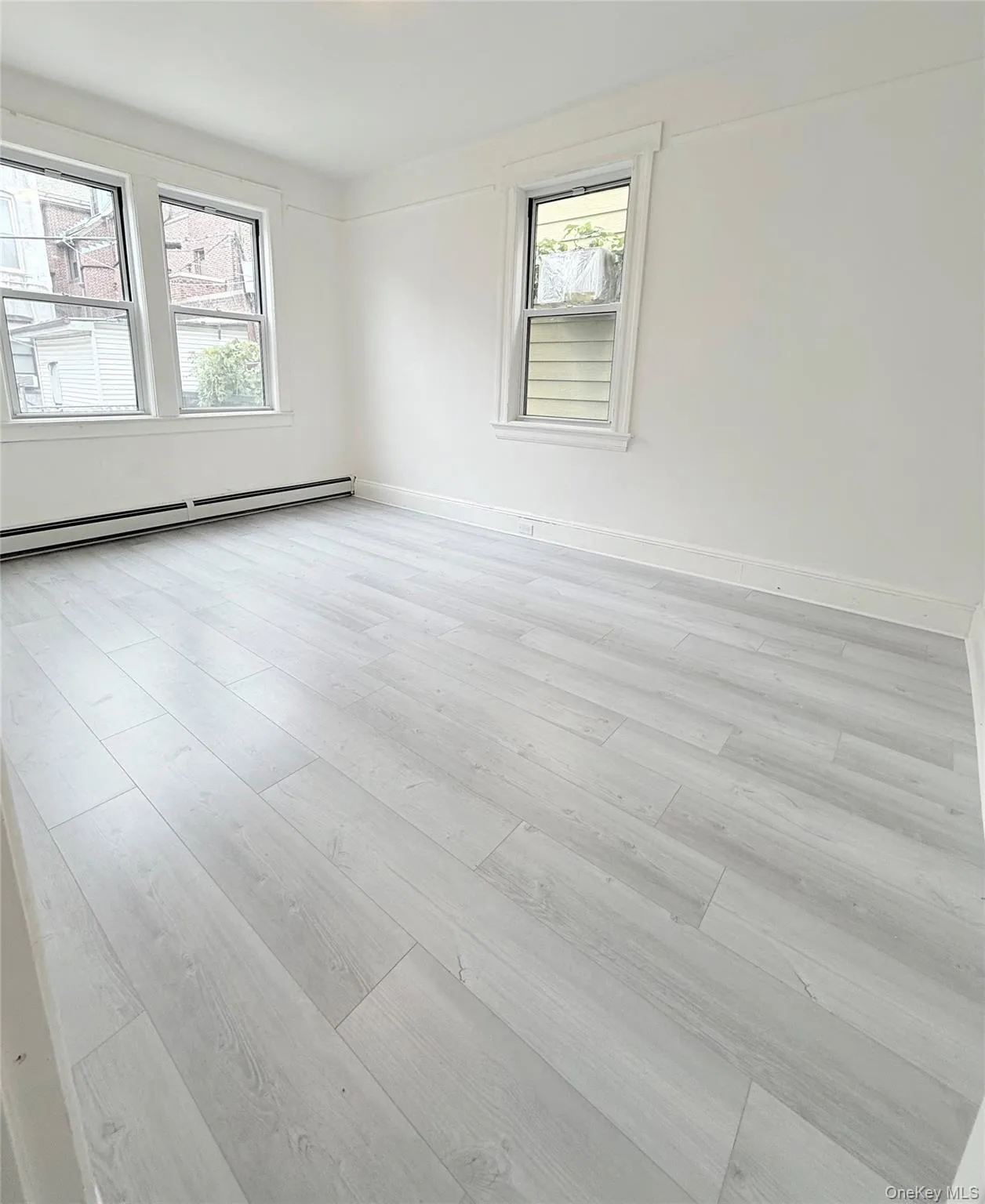 Unfurnished room featuring a baseboard heating unit and light wood-style floors Unfurnished room featuring a baseboard heating unit and light wood-style floors