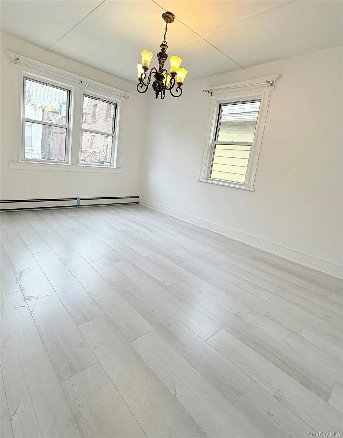 Unfurnished room with a chandelier, light wood-type flooring, and a baseboard radiator Unfurnished room with a chandelier, light wood-type flooring, and a baseboard radiator