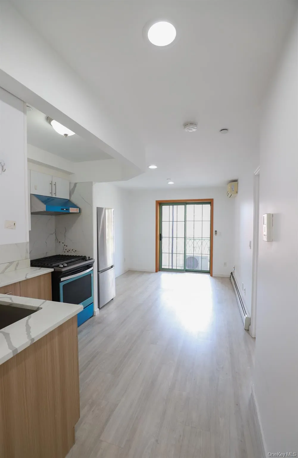 Kitchen featuring range with gas cooktop, light wood-type flooring, freestanding refrigerator, recessed lighting, and under cabinet range hood Kitchen featuring range with gas cooktop, light wood-type flooring, freestanding refrigerator, recessed lighting, and under cabinet range hood