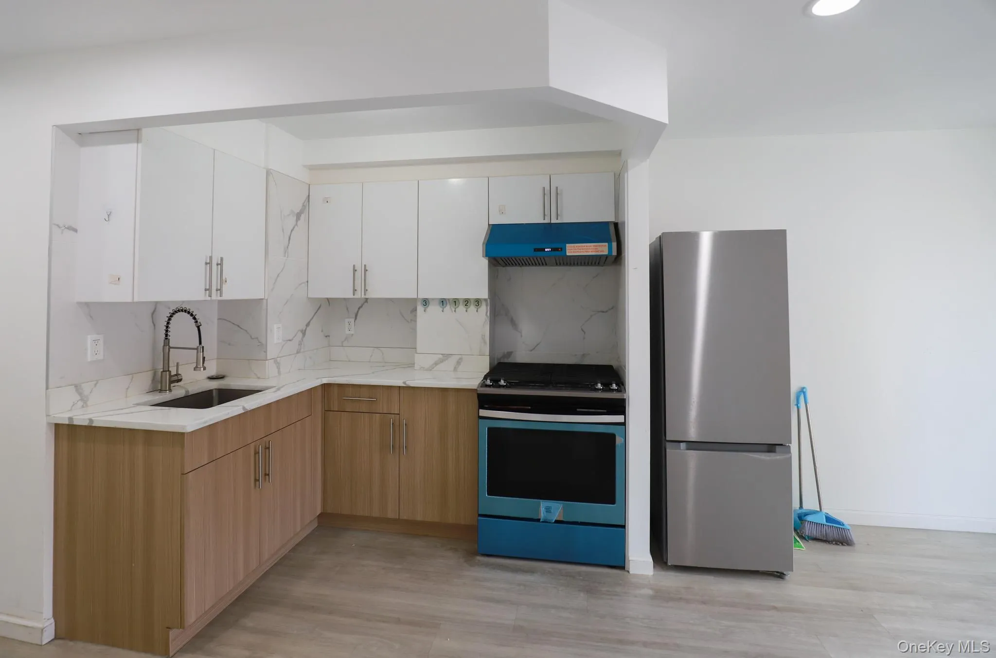 Kitchen with gas range oven, freestanding refrigerator, white cabinets, under cabinet range hood, and decorative backsplash Kitchen with gas range oven, freestanding refrigerator, white cabinets, under cabinet range hood, and decorative backsplash