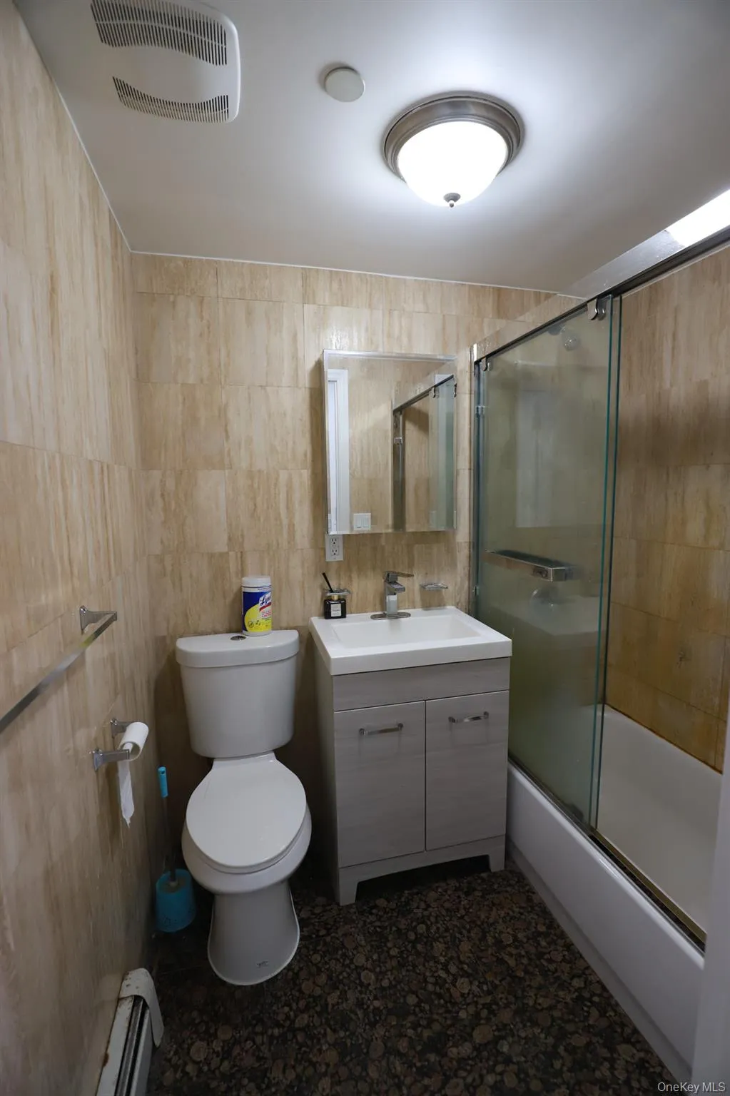 Bathroom with shower / bath combination with glass door, tile walls, vanity, and baseboard heating Bathroom with shower / bath combination with glass door, tile walls, vanity, and baseboard heating