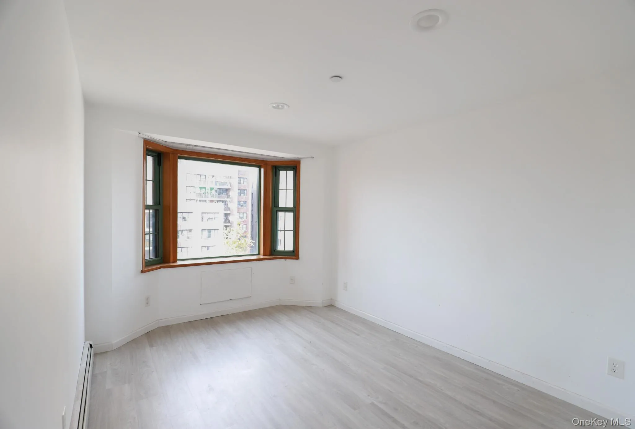 Unfurnished room featuring a baseboard heating unit and light wood-type flooring Unfurnished room featuring a baseboard heating unit and light wood-type flooring