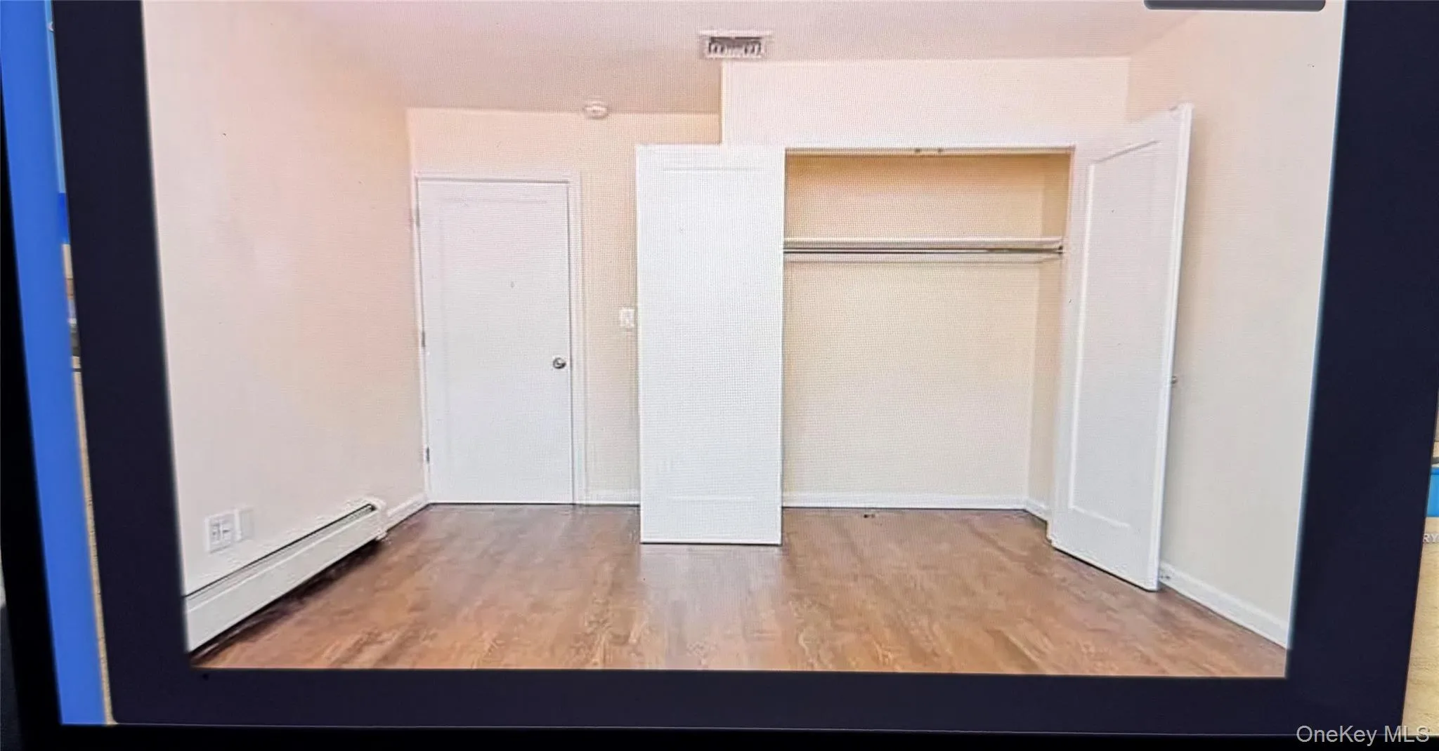Unfurnished bedroom featuring light wood-type flooring, a baseboard radiator, and a closet Unfurnished bedroom featuring light wood-type flooring, a baseboard radiator, and a closet