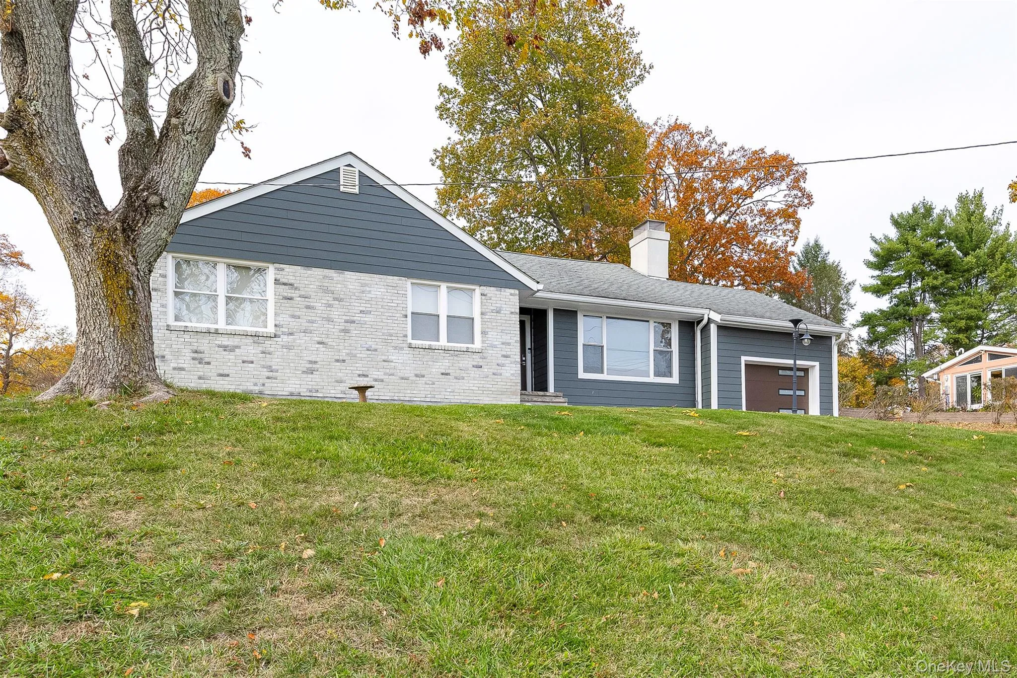 View of front facade featuring a front lawn, a garage, a chimney, and brick siding View of front facade featuring a front lawn, a garage, a chimney, and brick siding