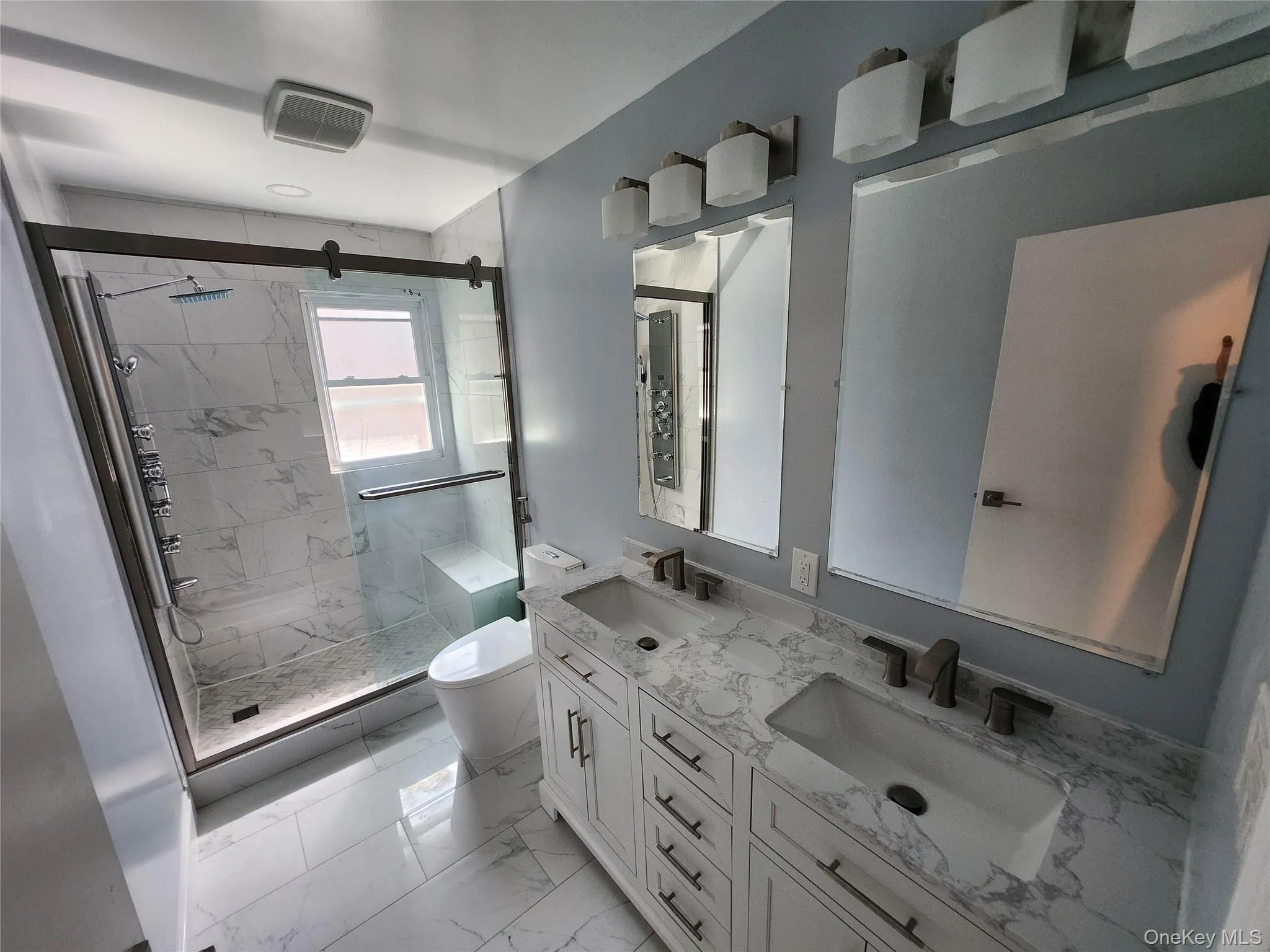 Full bathroom with marble finish floor, a sink, toilet, and a shower stall Full bathroom with marble finish floor, a sink, toilet, and a shower stall