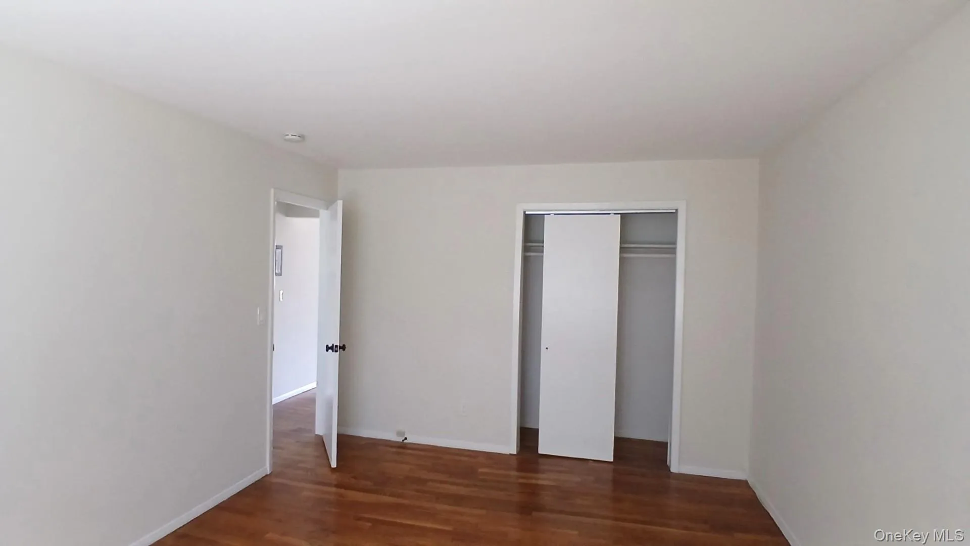 Unfurnished bedroom with dark wood-style flooring and a closet Unfurnished bedroom with dark wood-style flooring and a closet