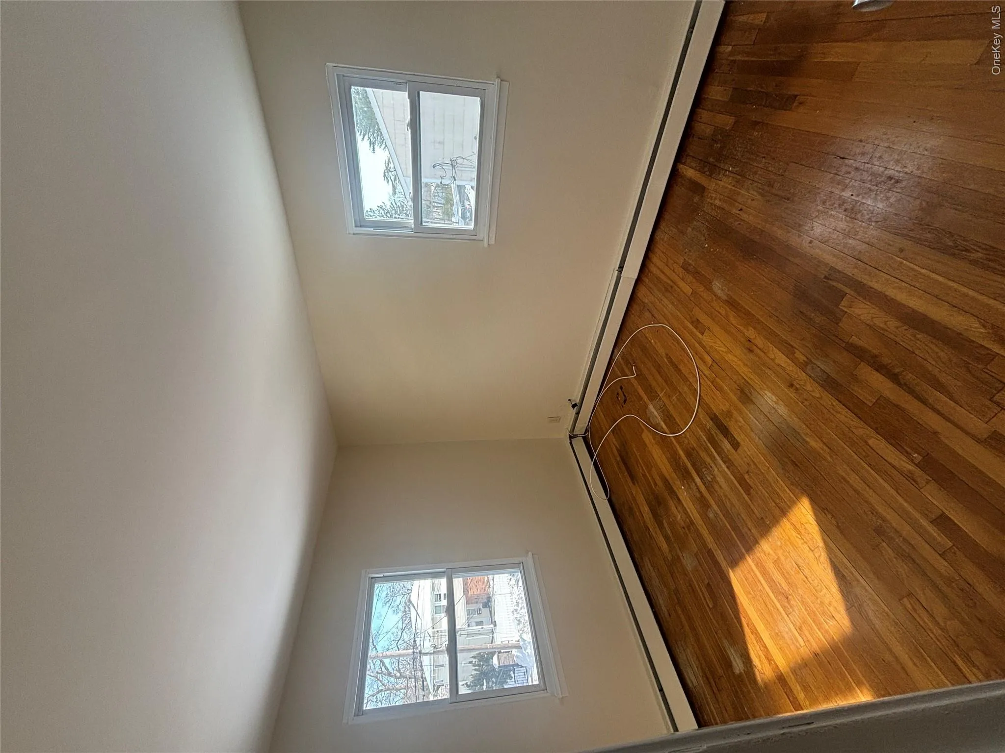 Spare room with dark wood-style flooring, baseboard heating, and plenty of natural light Spare room with dark wood-style flooring, baseboard heating, and plenty of natural light
