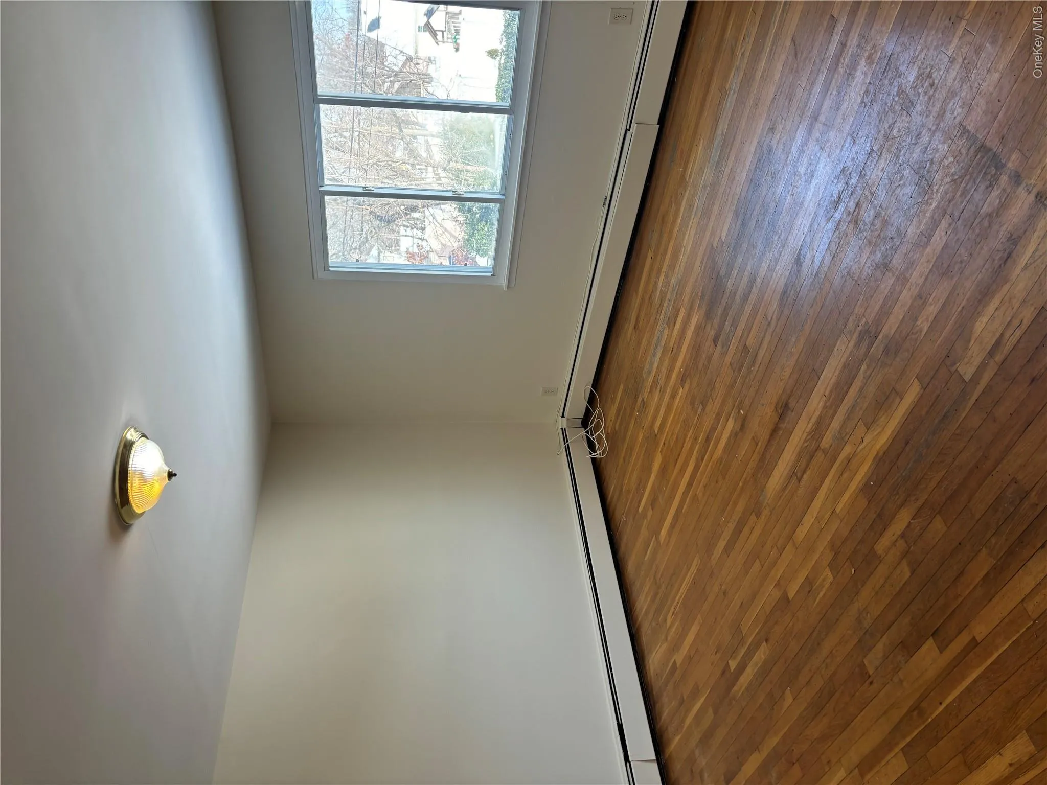 Spare room featuring dark wood-type flooring and baseboard heating Spare room featuring dark wood-type flooring and baseboard heating