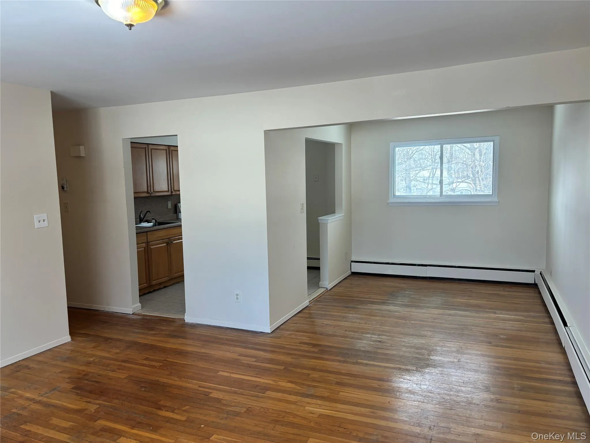 Unfurnished room featuring baseboard heating and dark wood-style floors Unfurnished room featuring baseboard heating and dark wood-style floors