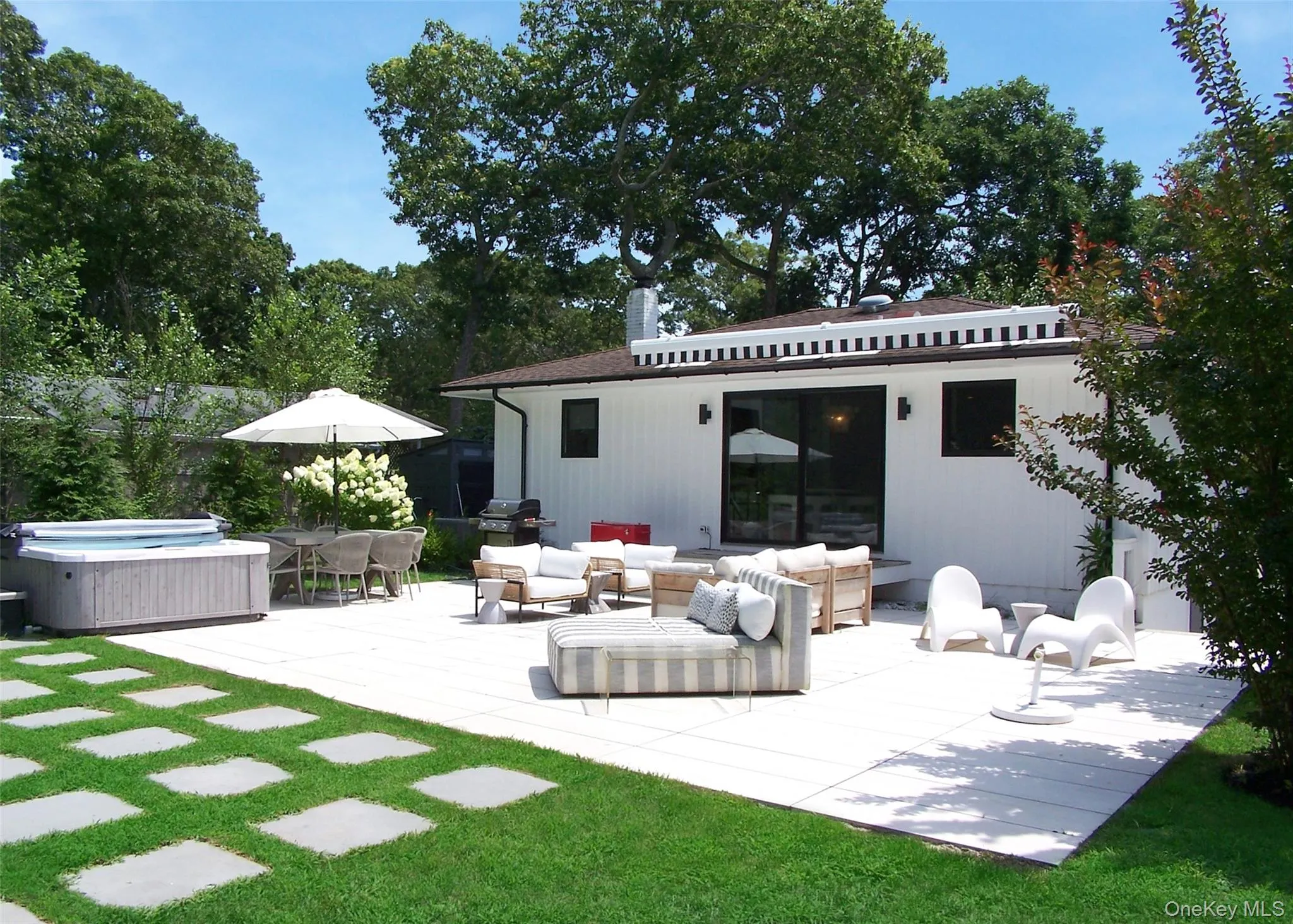 Rear view of house with an outdoor living space, a hot tub, outdoor dining space, a patio, and view of scattered trees Rear view of house with an outdoor living space, a hot tub, outdoor dining space, a patio, and view of scattered trees