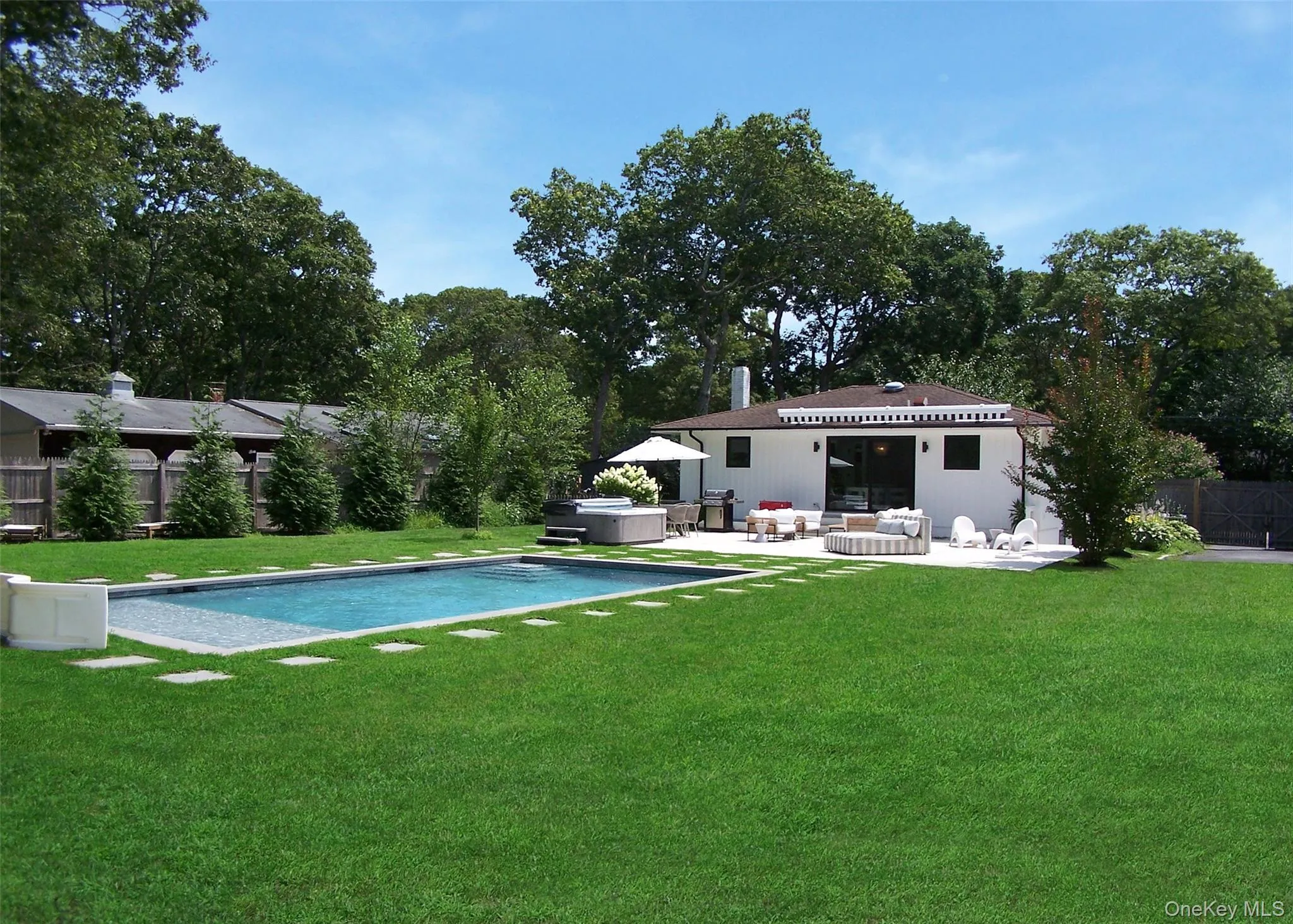 View of swimming pool featuring a hot tub, a patio, view of scattered trees, and a grill View of swimming pool featuring a hot tub, a patio, view of scattered trees, and a grill