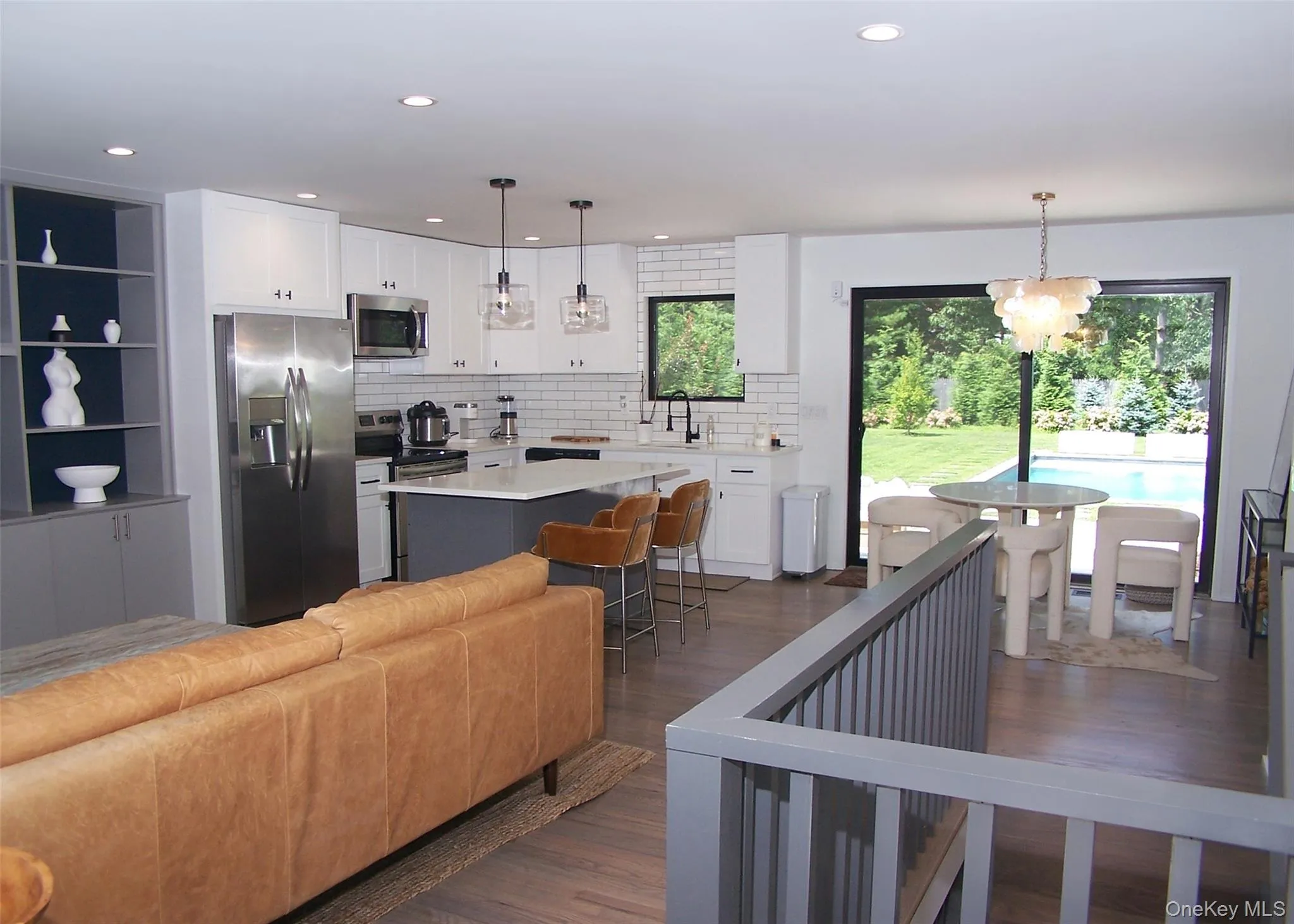 Kitchen featuring stainless steel appliances, dark wood-type flooring, a kitchen island, white cabinets, and backsplash Kitchen featuring stainless steel appliances, dark wood-type flooring, a kitchen island, white cabinets, and backsplash