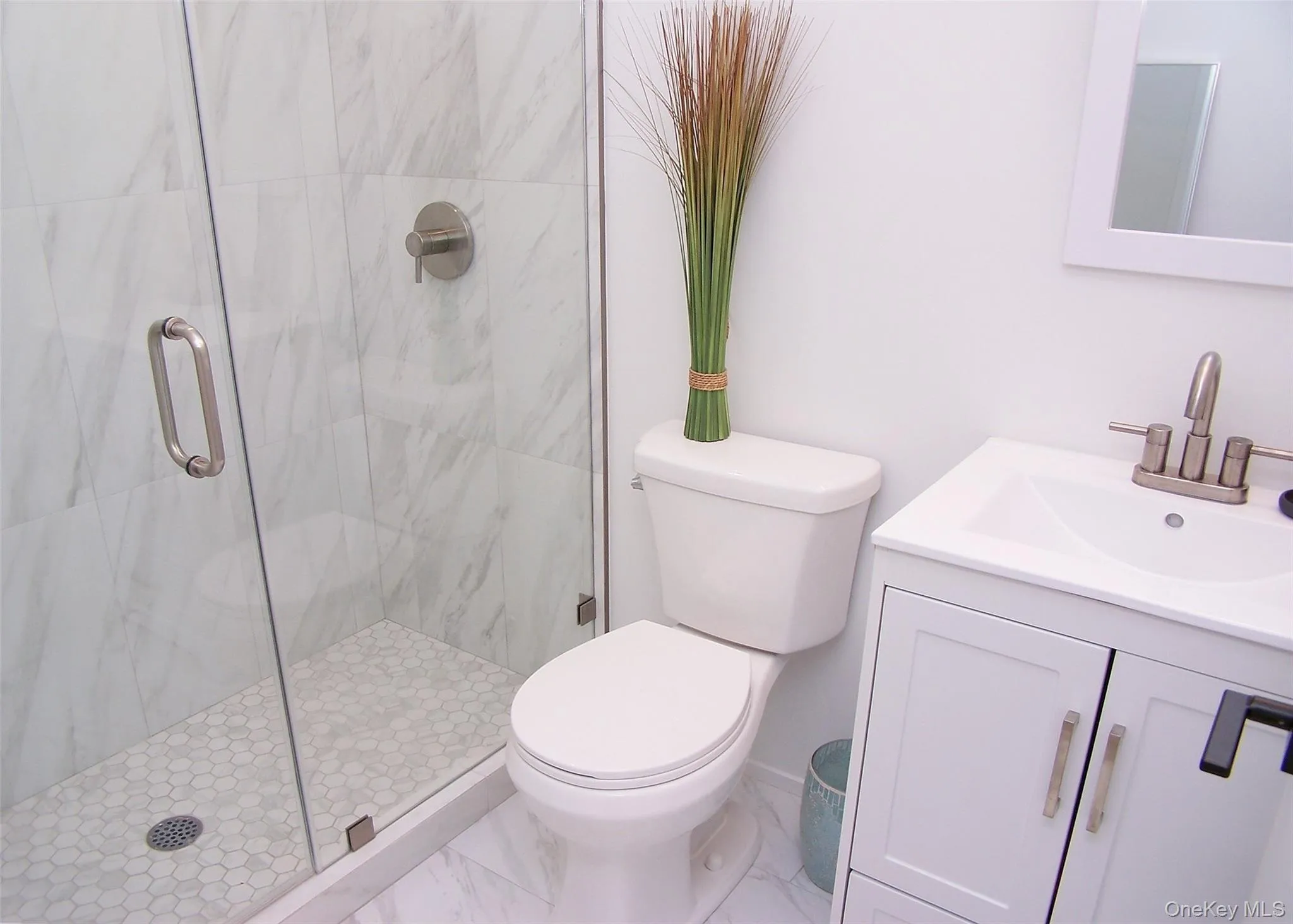 Bathroom featuring a marble finish shower, vanity, and marble look tile flooring Bathroom featuring a marble finish shower, vanity, and marble look tile flooring