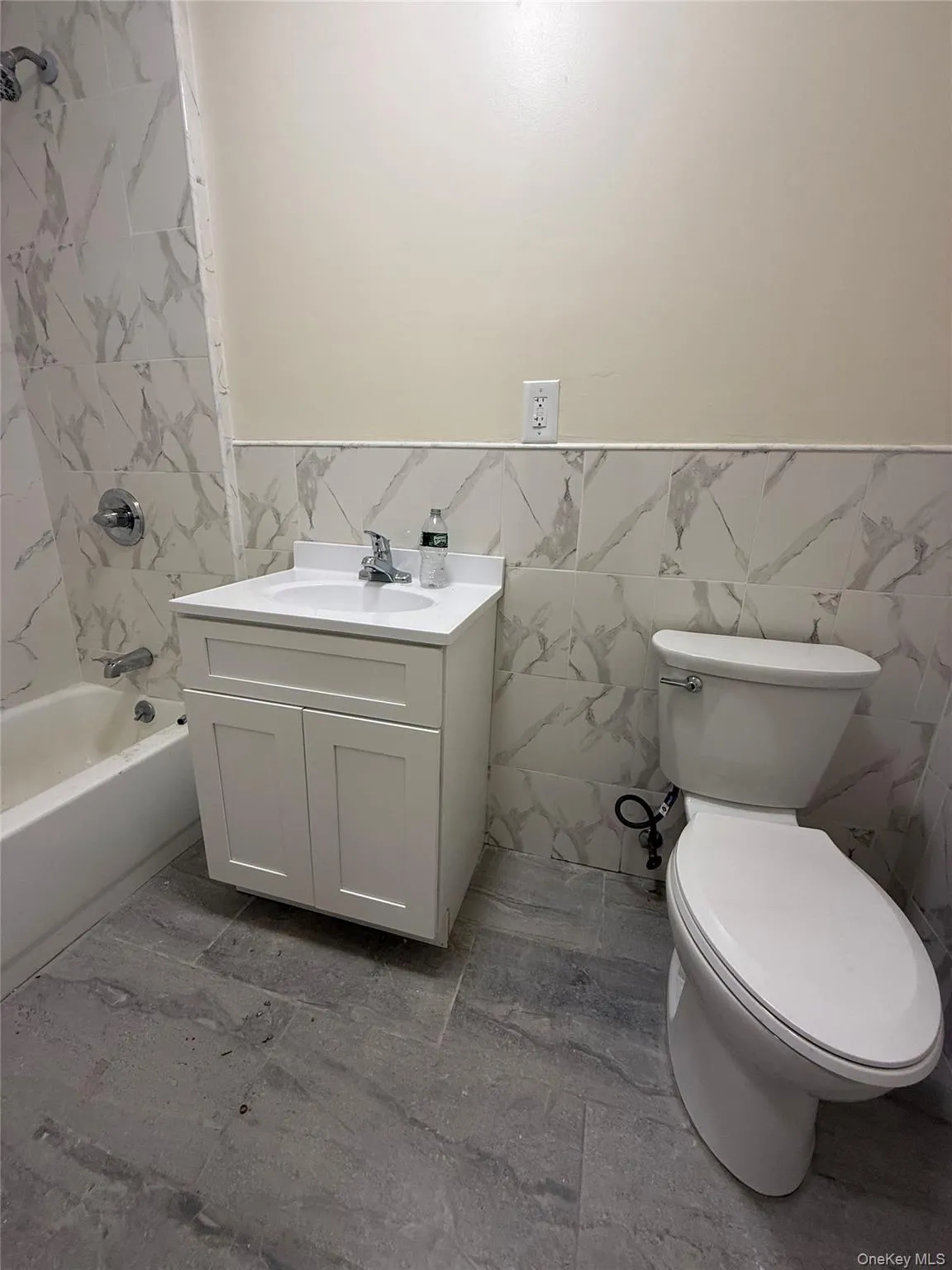 Full bathroom with tile walls, vanity, washtub / shower combination, and a wainscoted wall Full bathroom with tile walls, vanity, washtub / shower combination, and a wainscoted wall