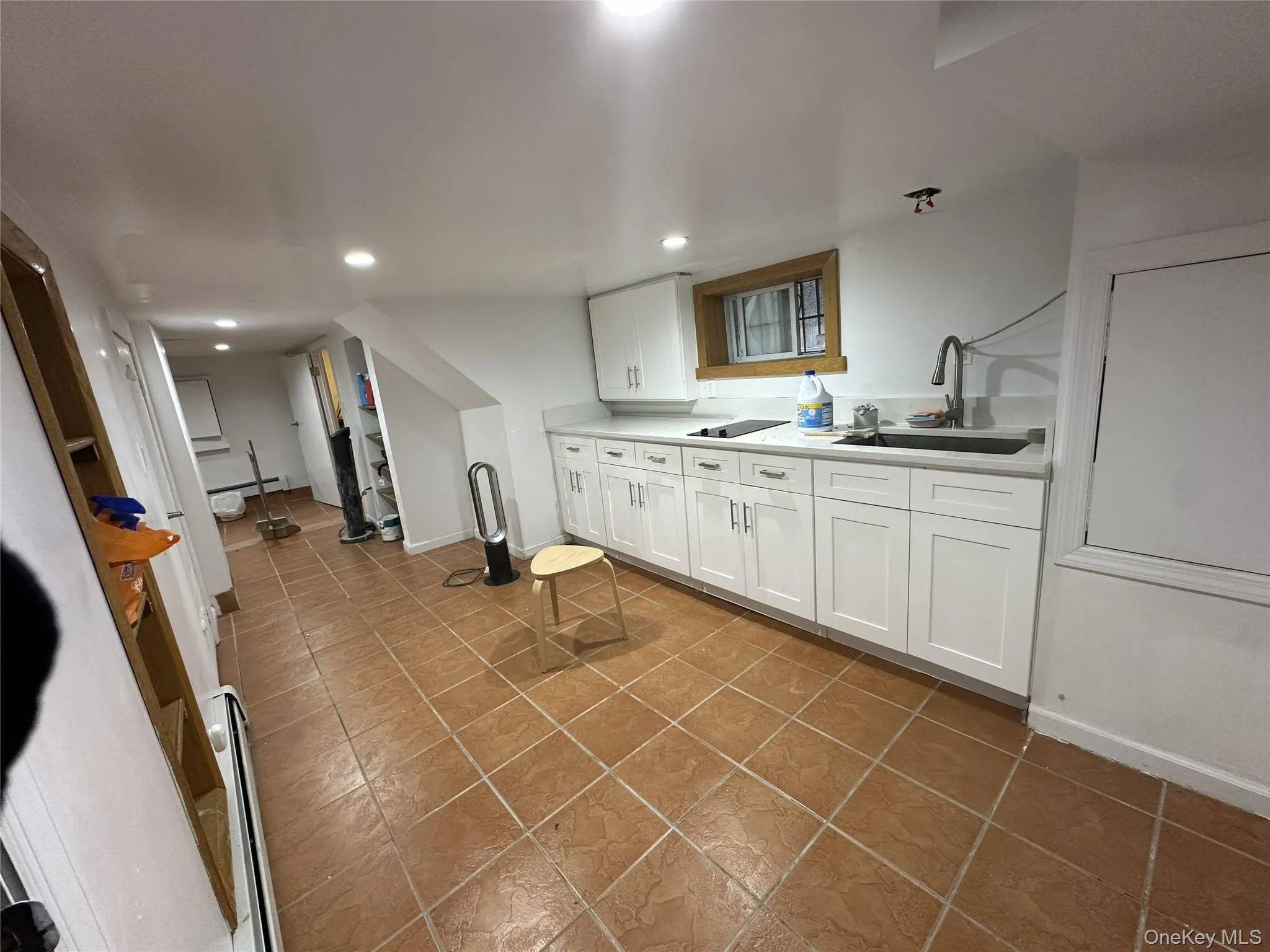 Kitchen with white cabinets, light countertops, dark tile patterned floors, and recessed lighting Kitchen with white cabinets, light countertops, dark tile patterned floors, and recessed lighting