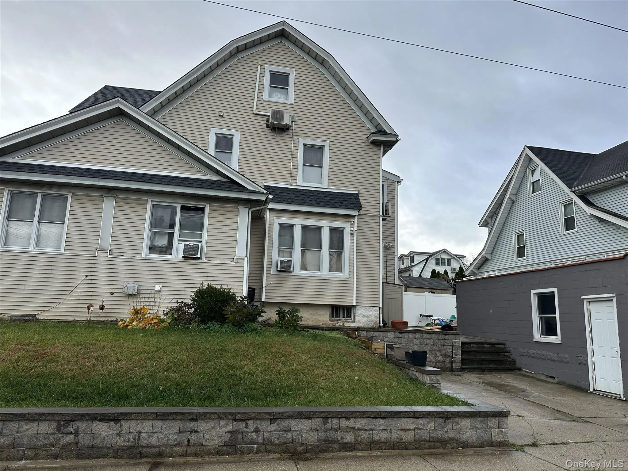 Rear view of property with a shingled roof, a yard, and a wall unit AC Rear view of property with a shingled roof, a yard, and a wall unit AC